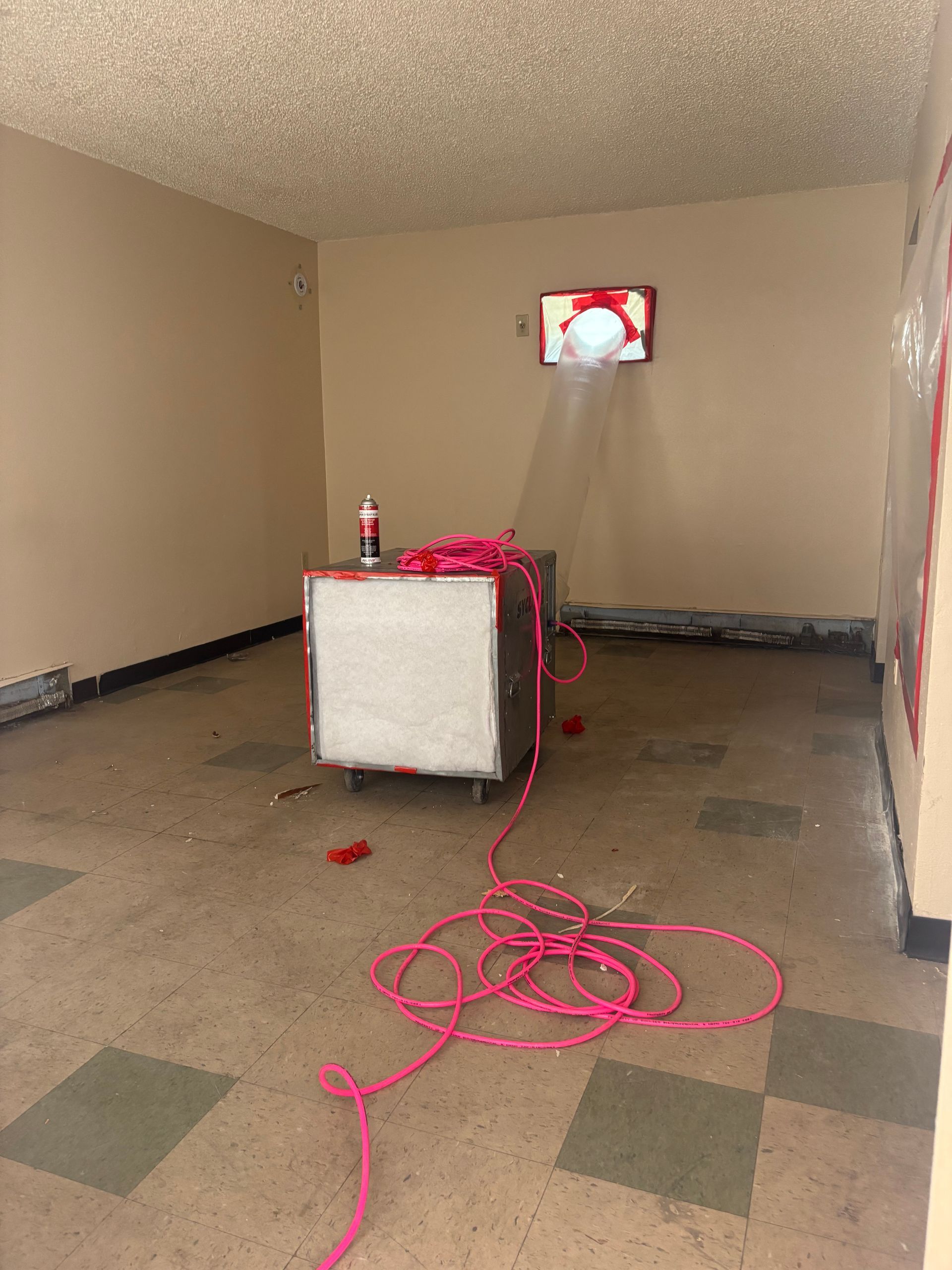 An empty room with a pink cord hanging from the floor.