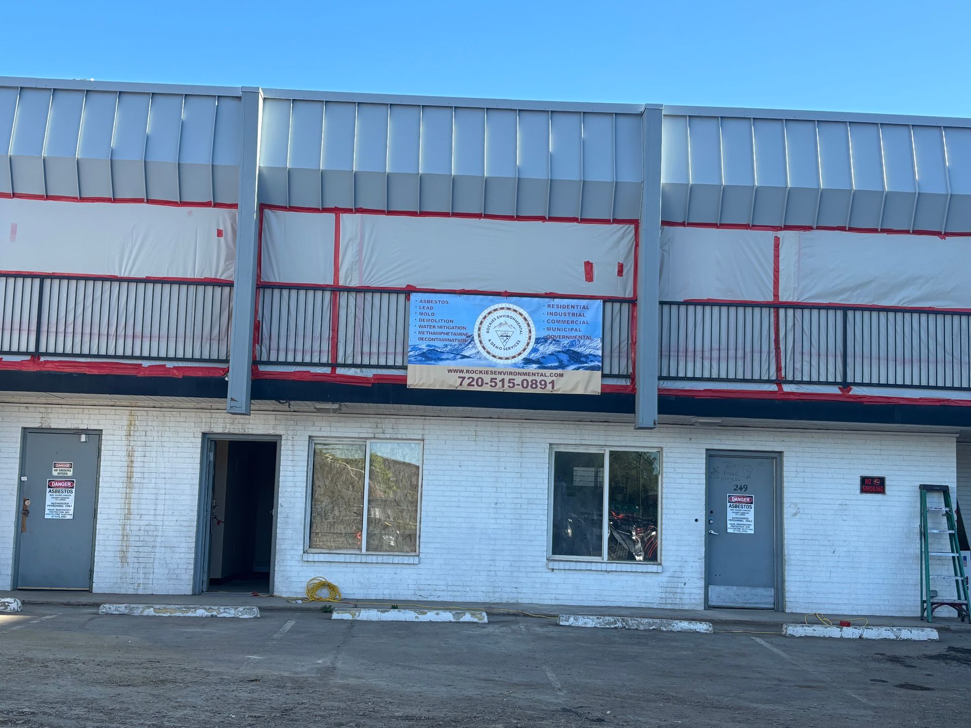 A white building with a balcony and a sign on the side of it.