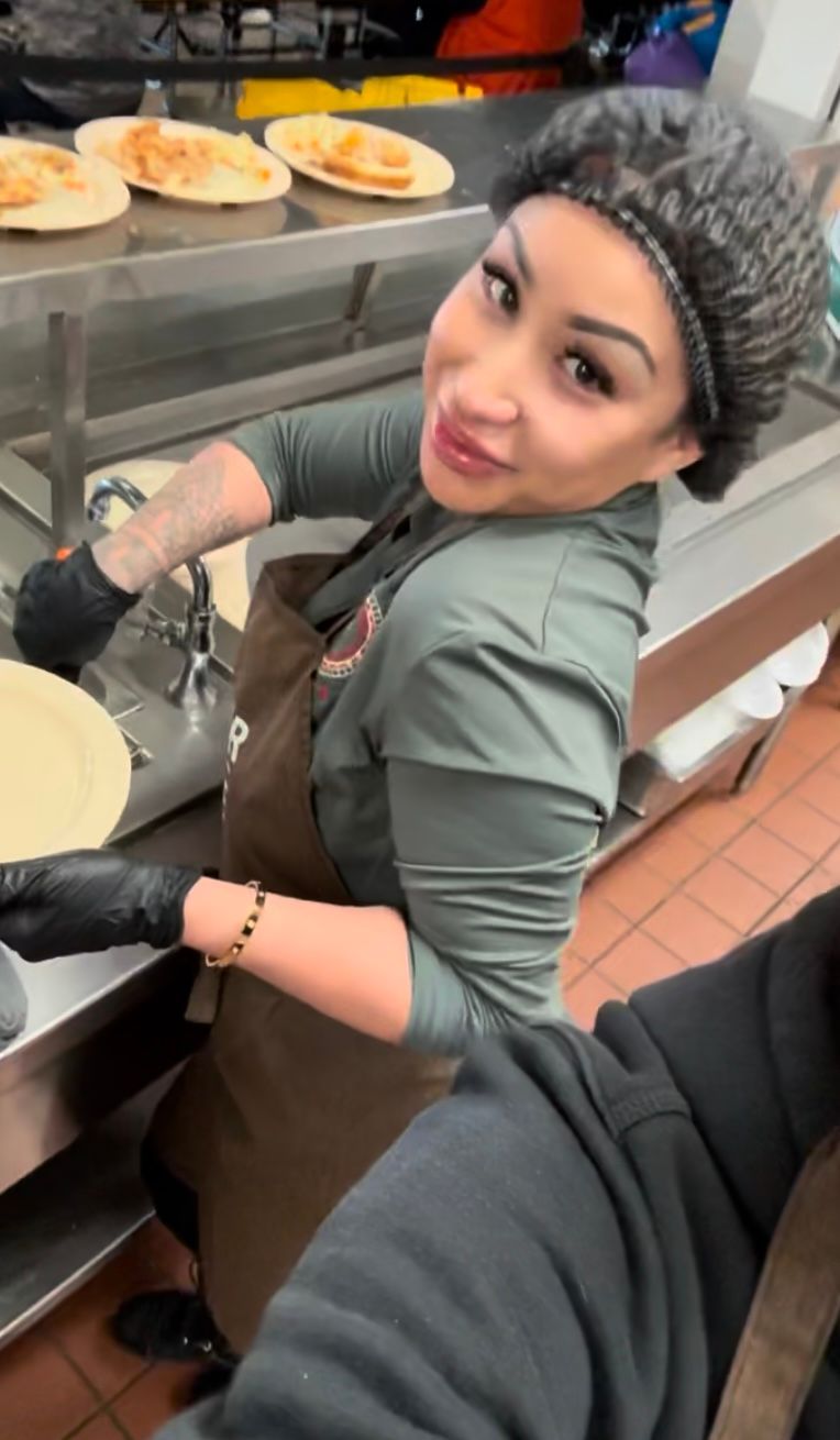 A woman is standing in a kitchen preparing food
