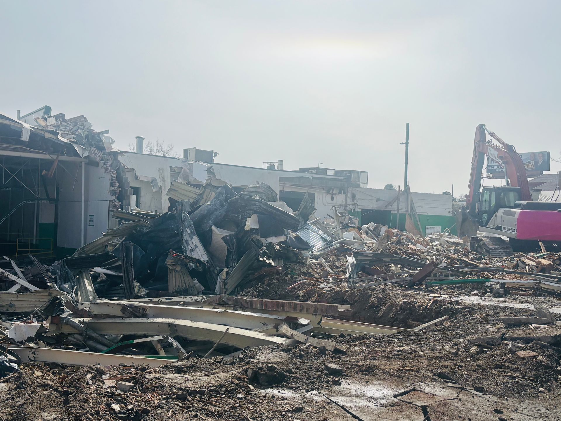 A building is being demolished with a large pile of rubble in the foreground.