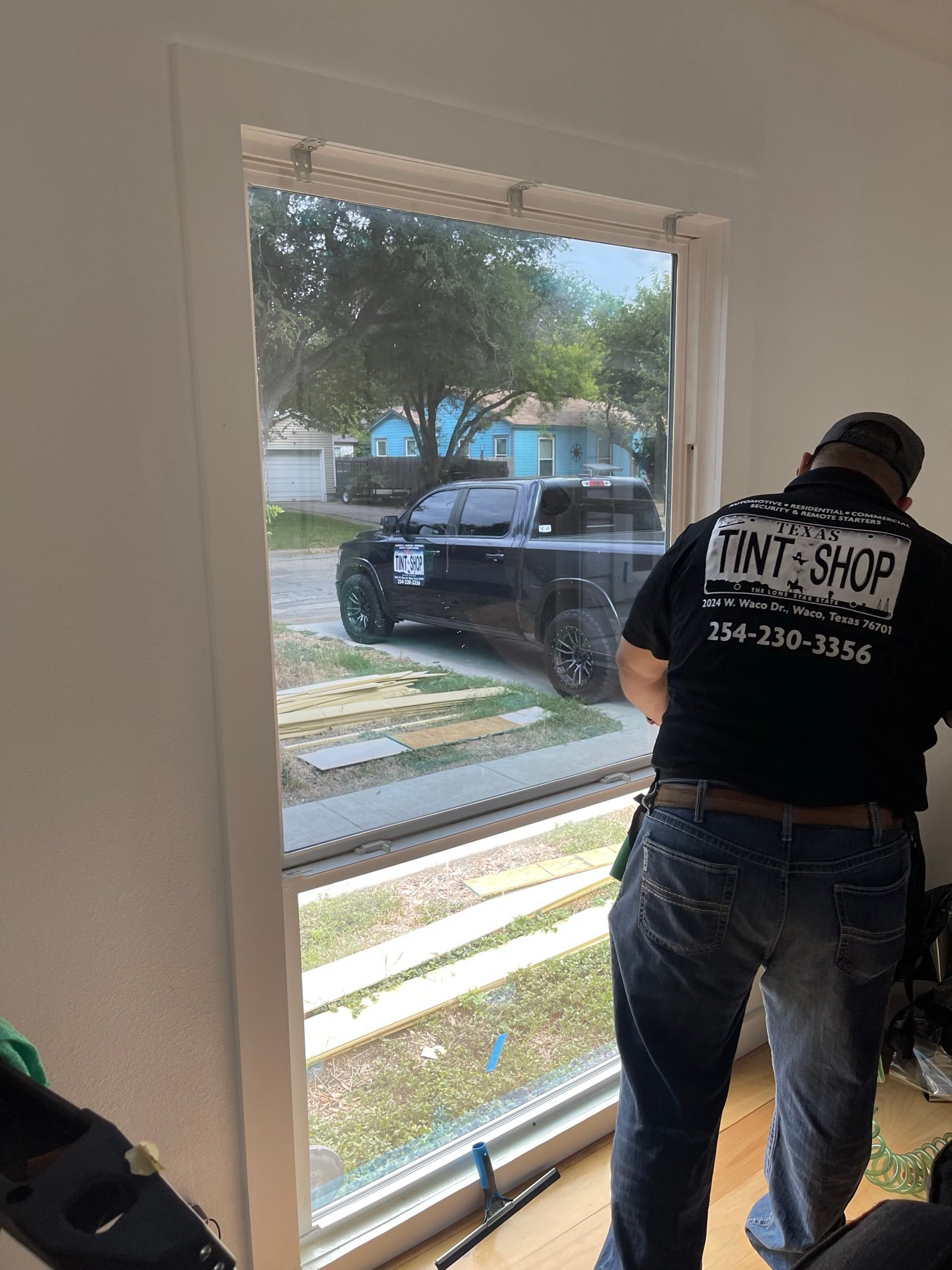 A man in a black shirt is standing in front of a window.