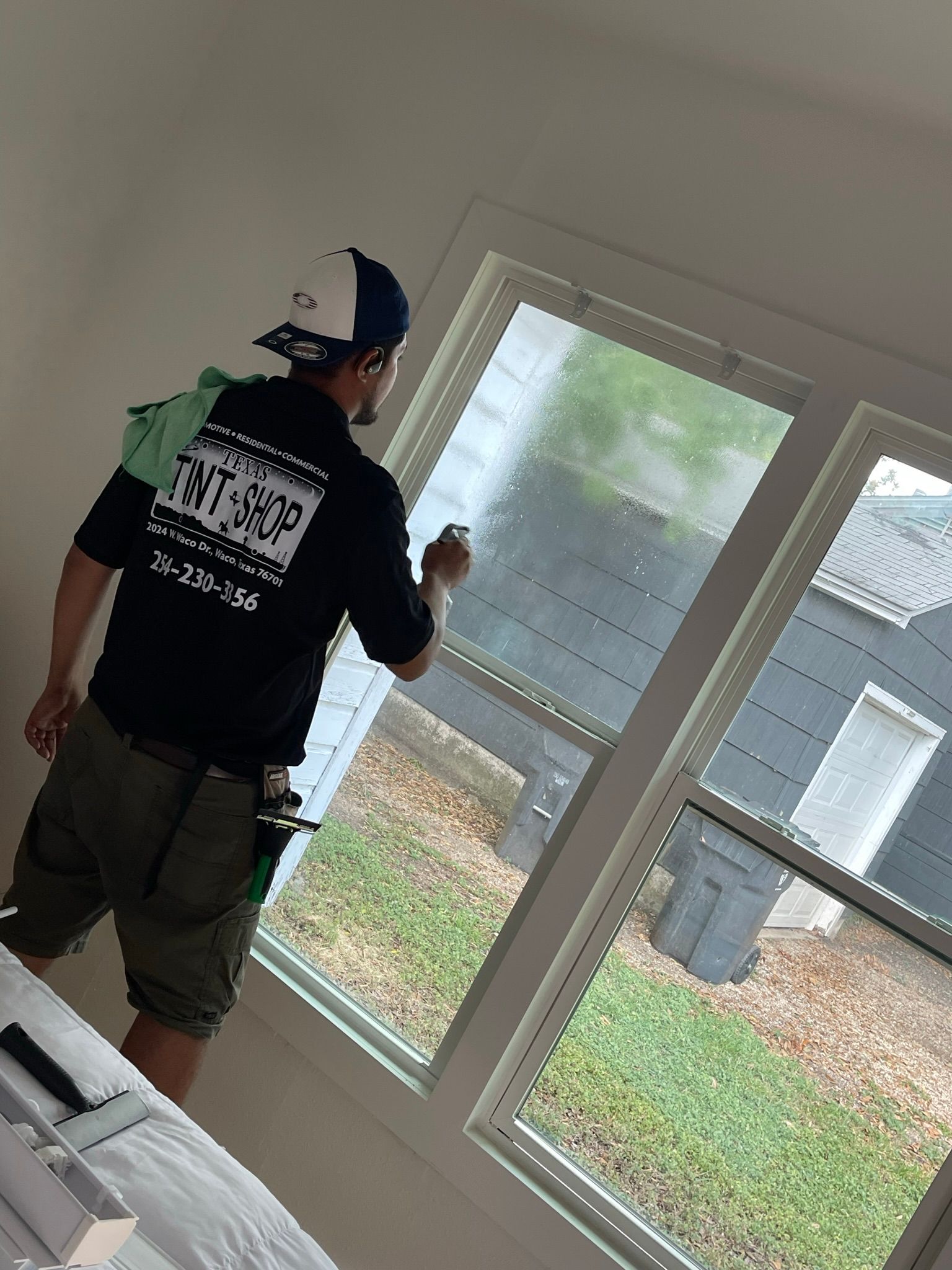 A man is cleaning a window with a green cloth.