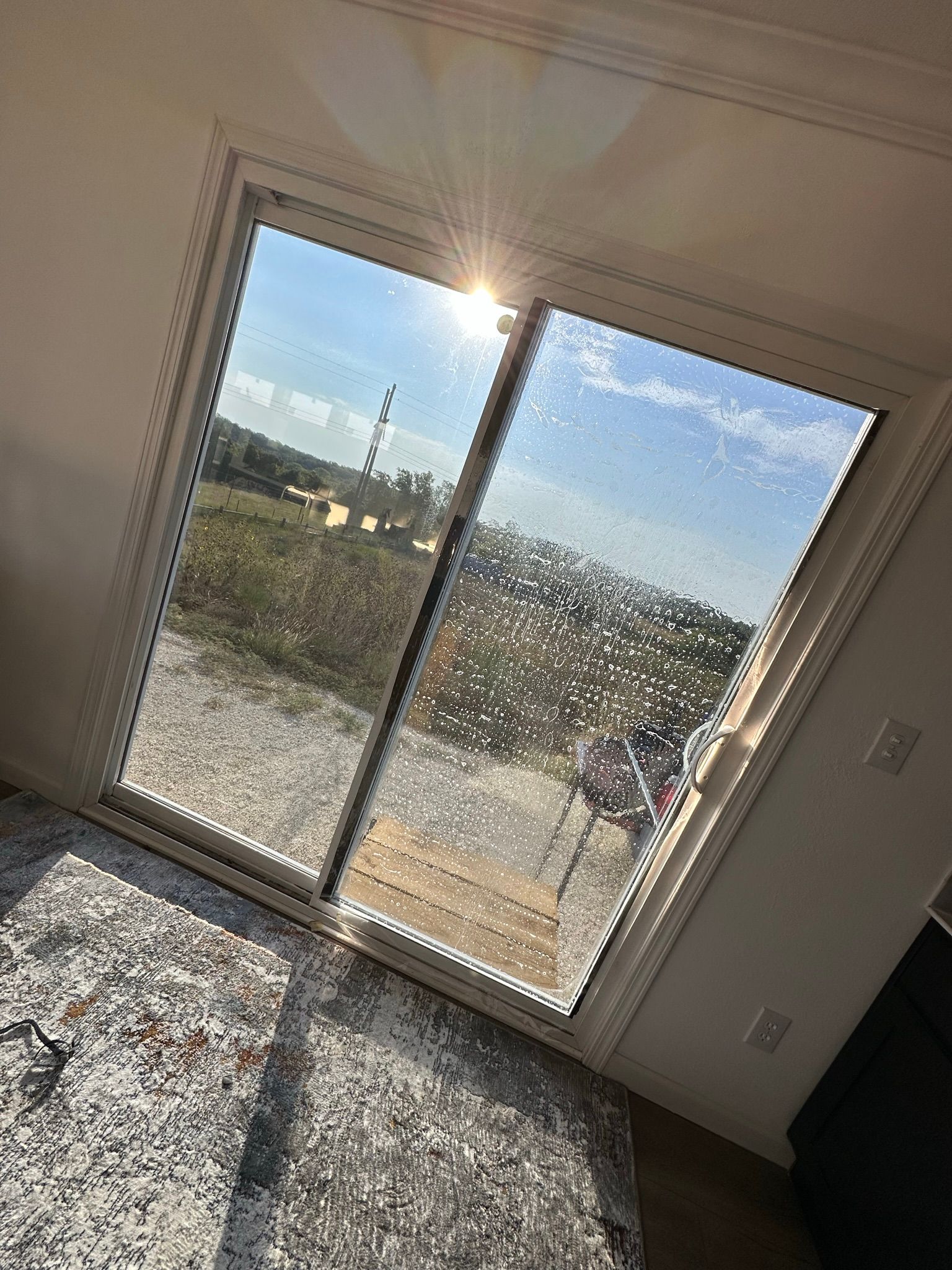 The sun is shining through a sliding glass door in a living room.