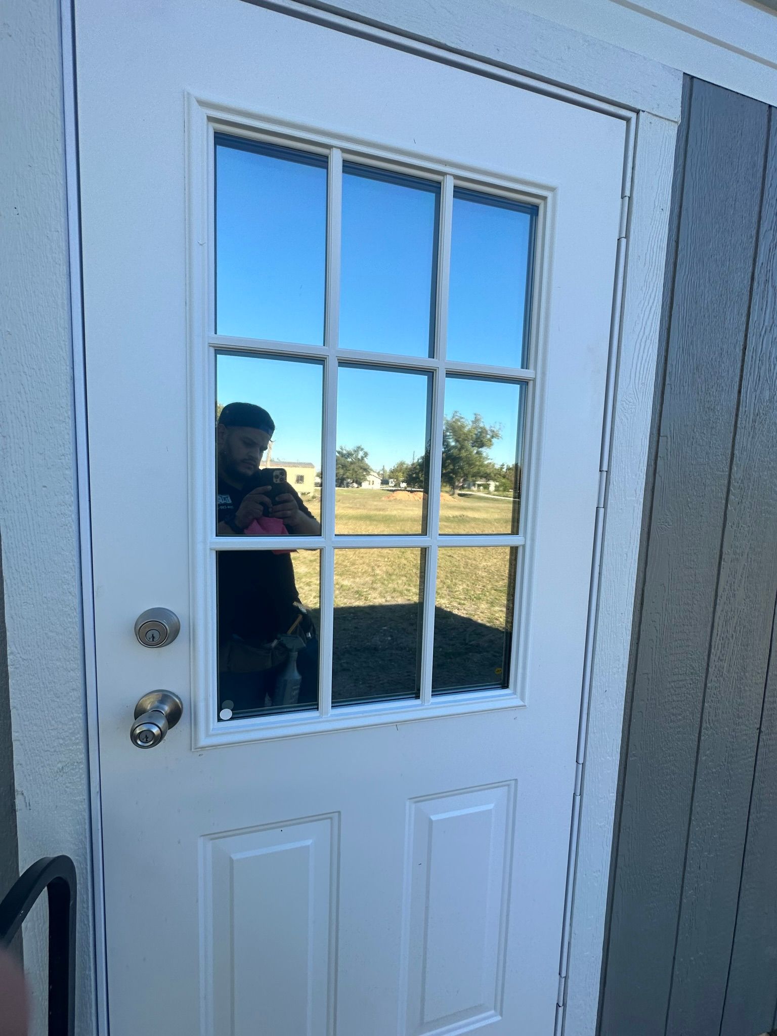 A man is taking a picture of himself in the window of a door.