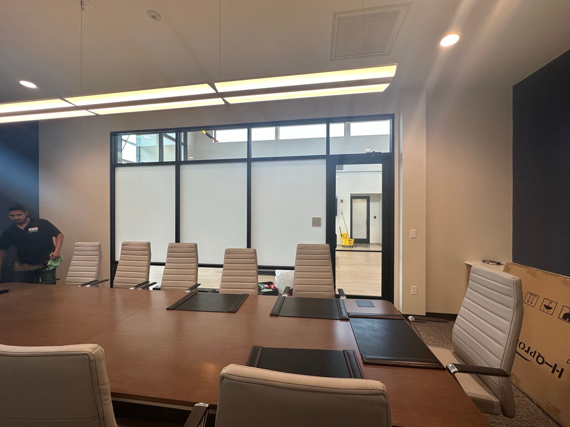A man is standing in a conference room with a long table and chairs.