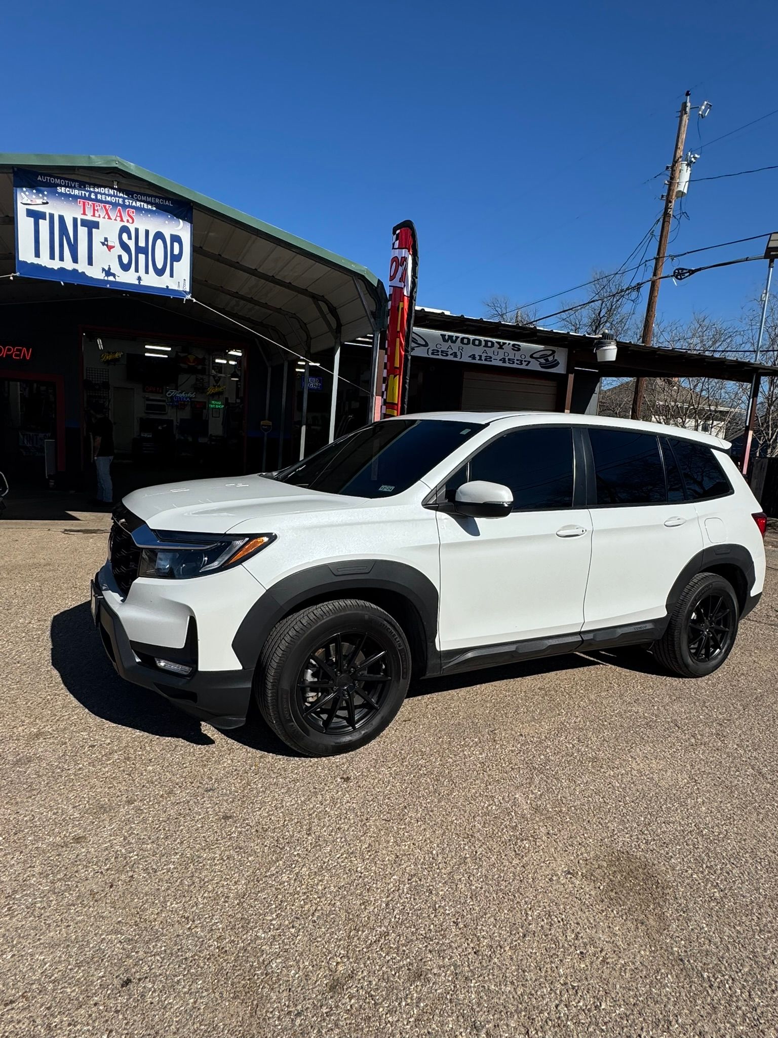 A white suv is parked in front of a tint shop.