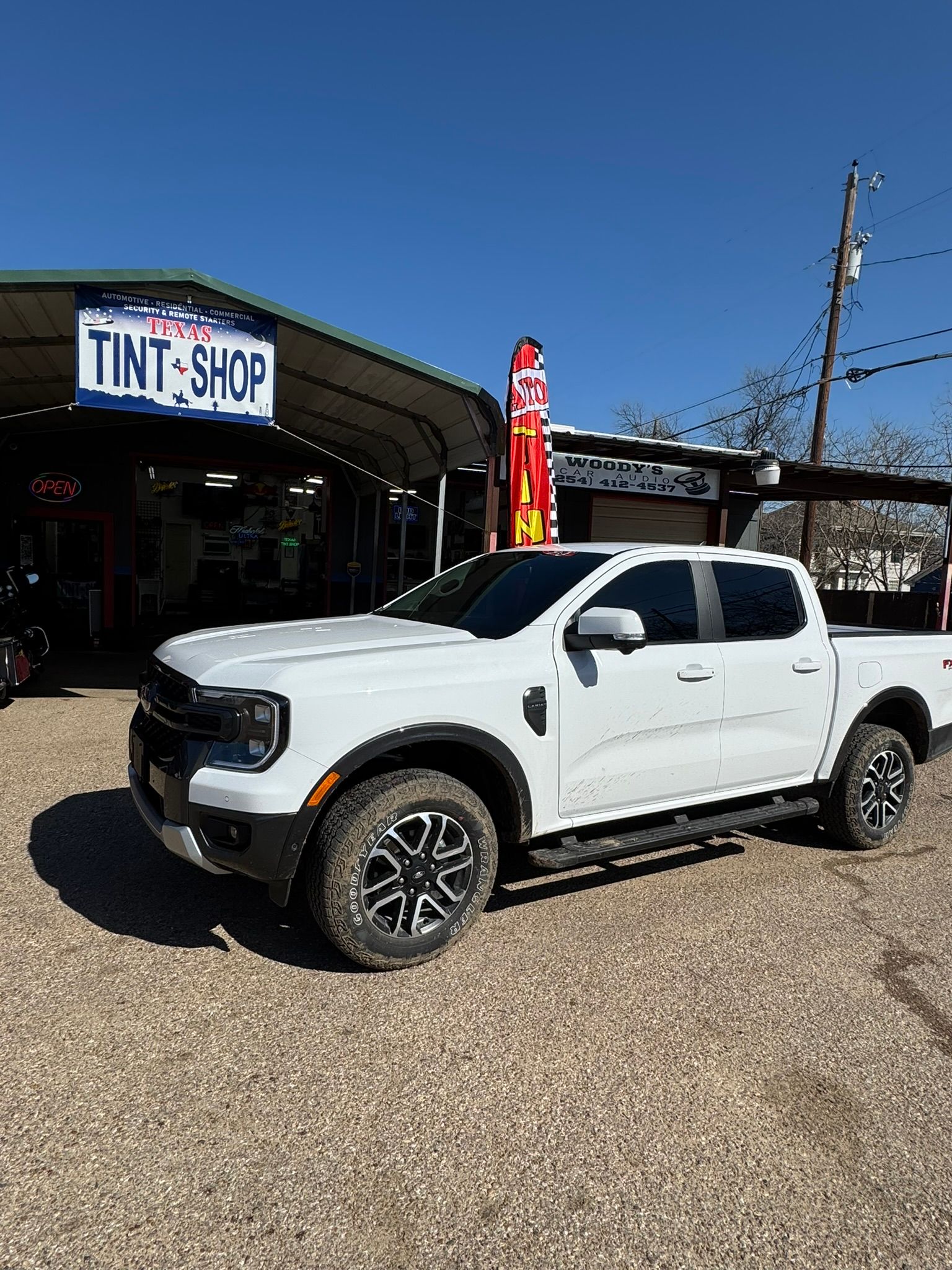 A white truck is parked in front of a tint shop.