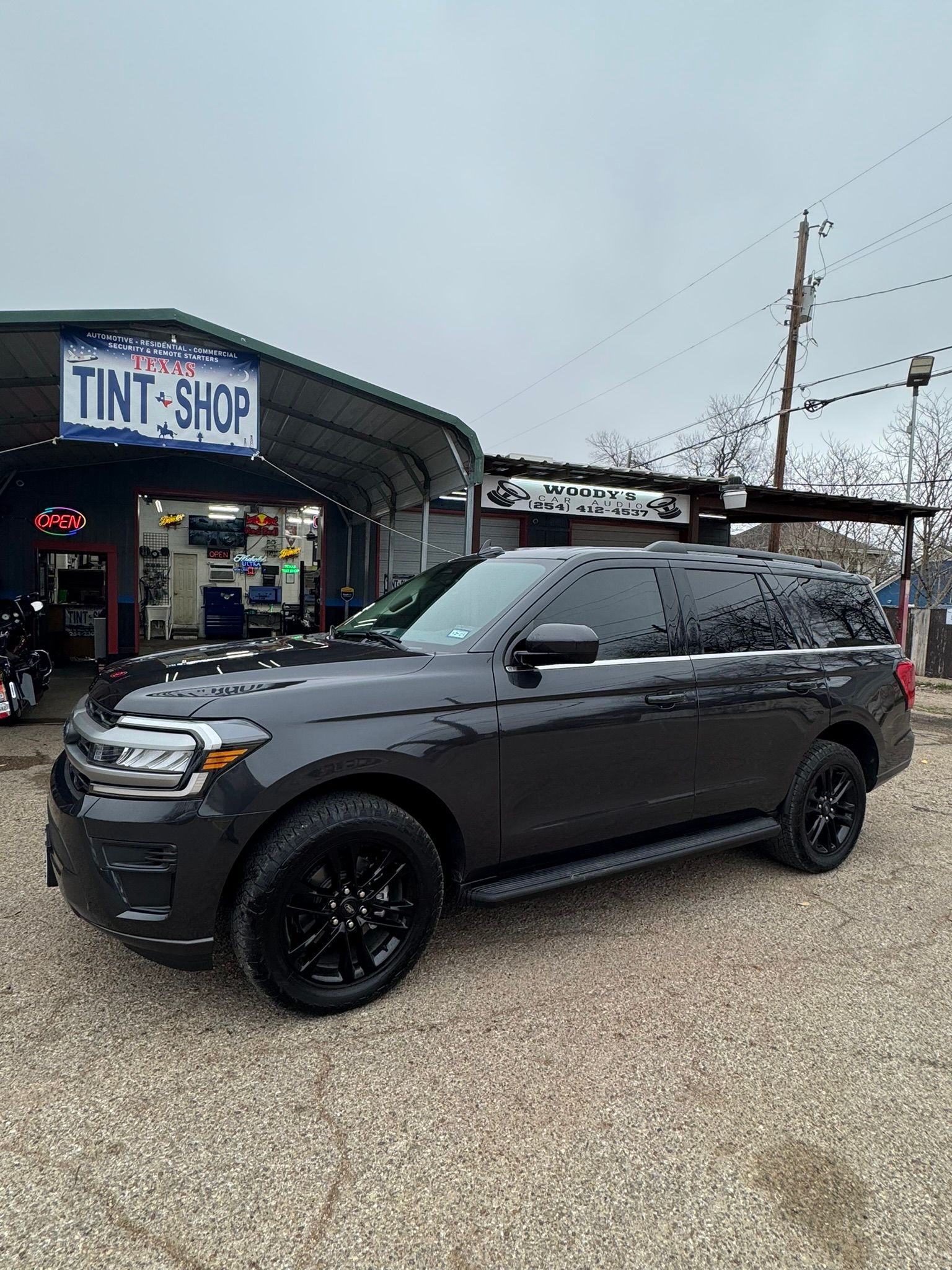 A black suv is parked in front of a tint shop.