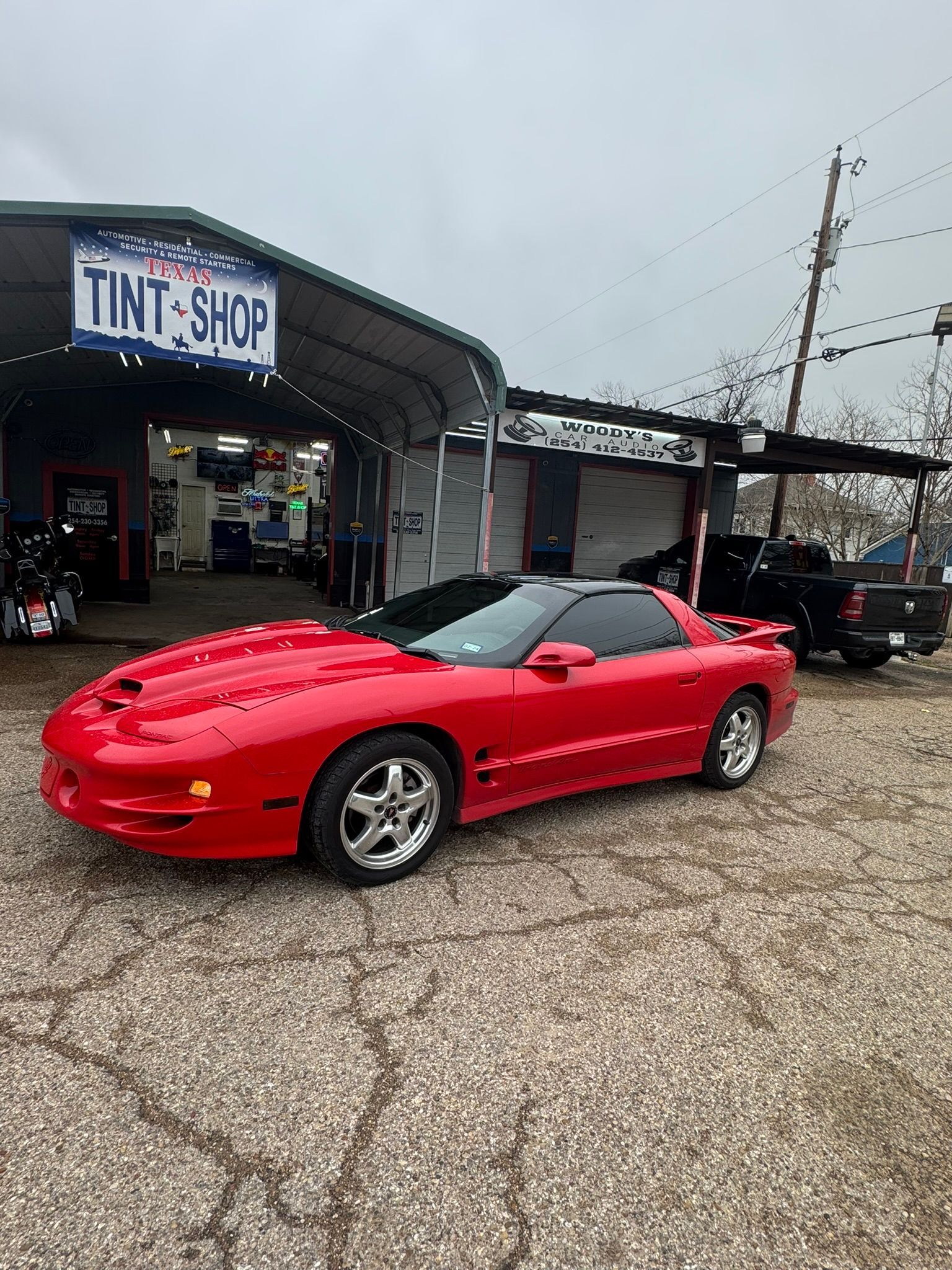 A red sports car is parked in front of a tint shop.