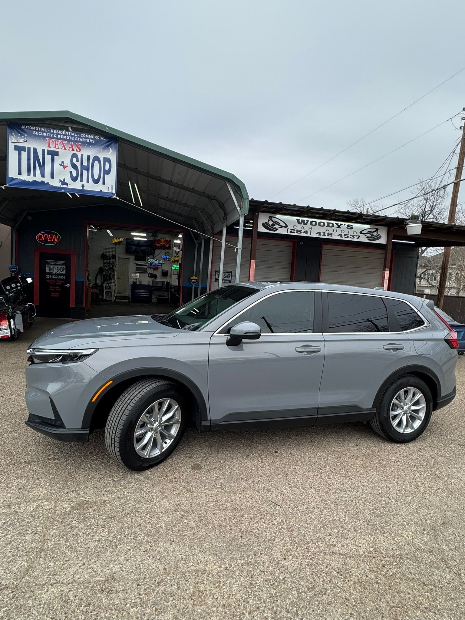 A gray suv is parked in front of a tint shop.