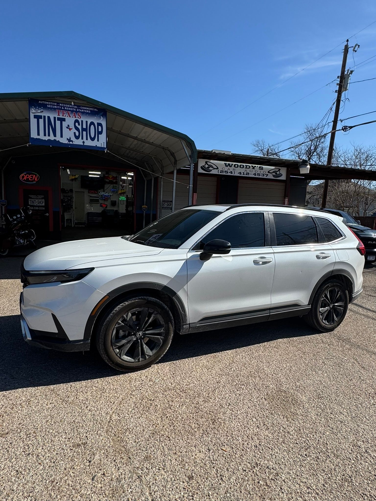 A white suv is parked in front of a tint shop.