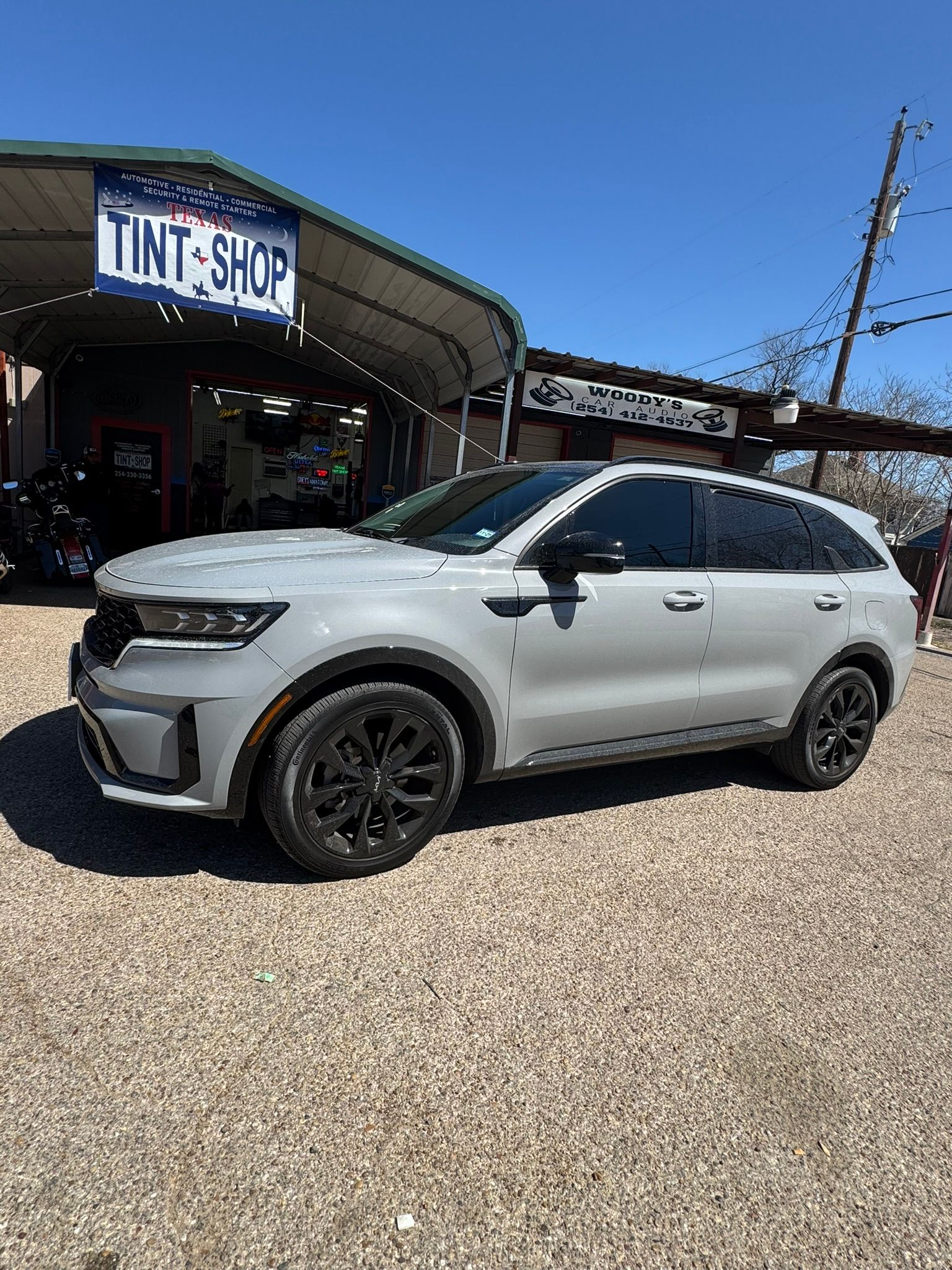 A white suv is parked in front of a tint shop.