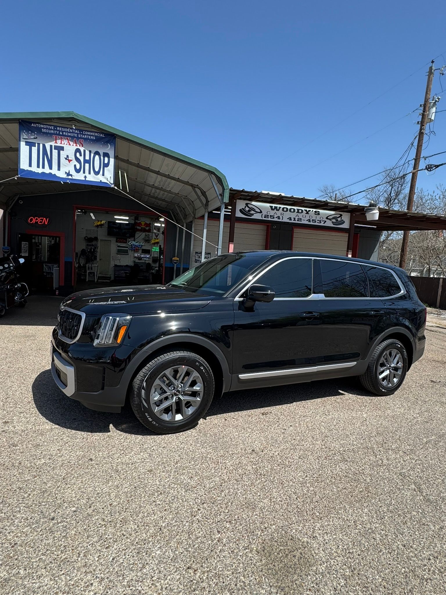 A black suv is parked in front of a tint shop.