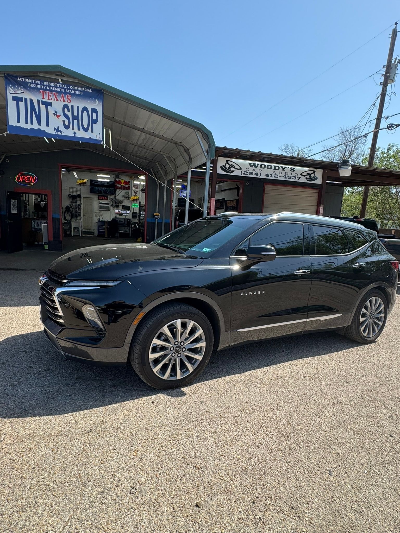 A black car is parked in front of a tint shop.