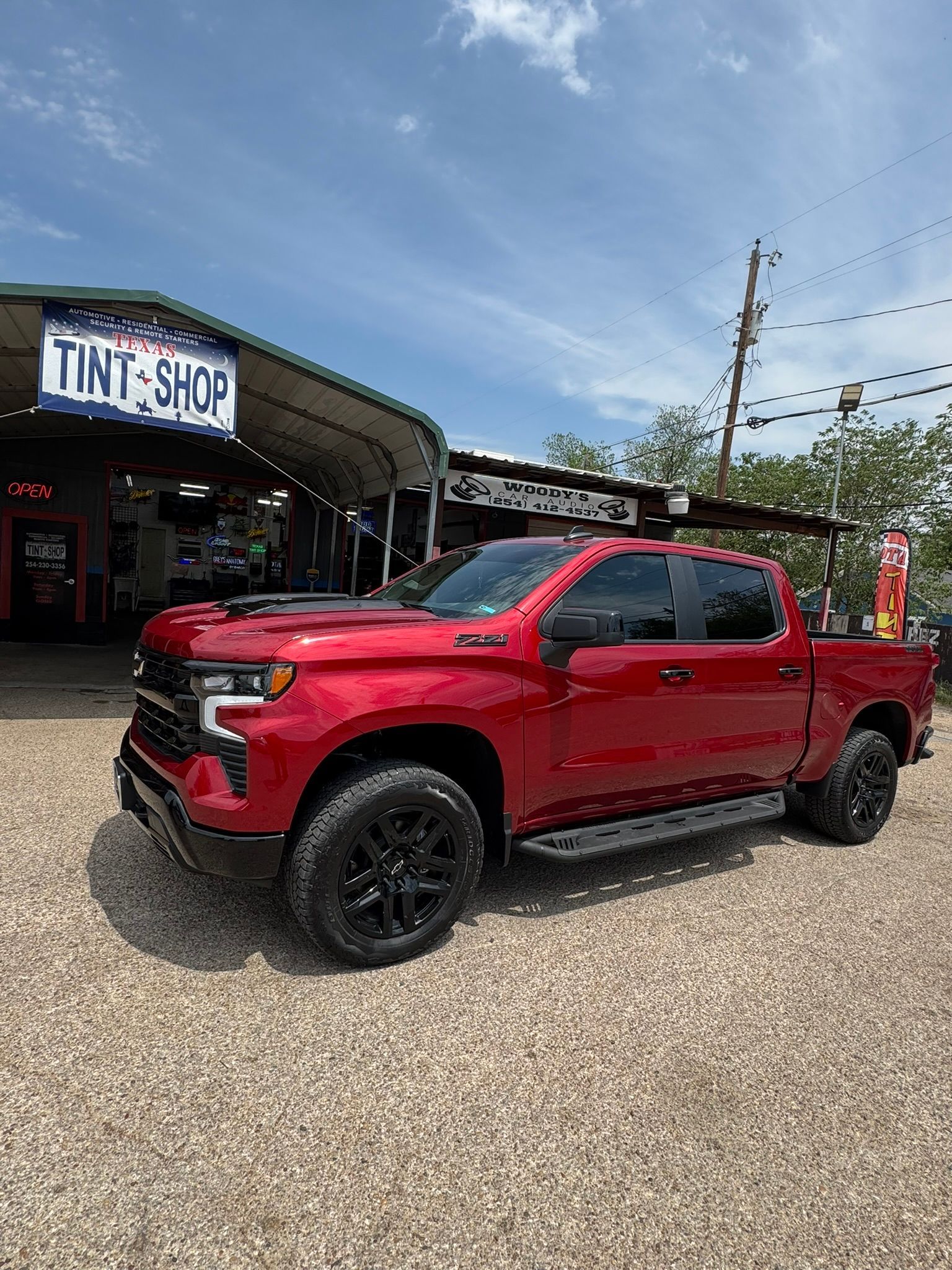 A red truck is parked in front of a tint shop.