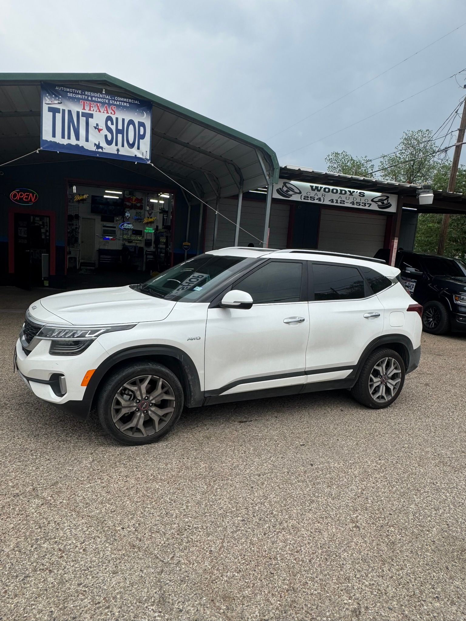 A white car is parked in front of a tint shop.