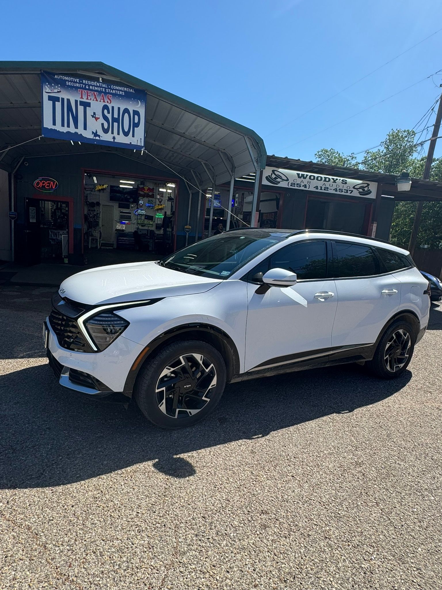 A white suv is parked in front of a tint shop.