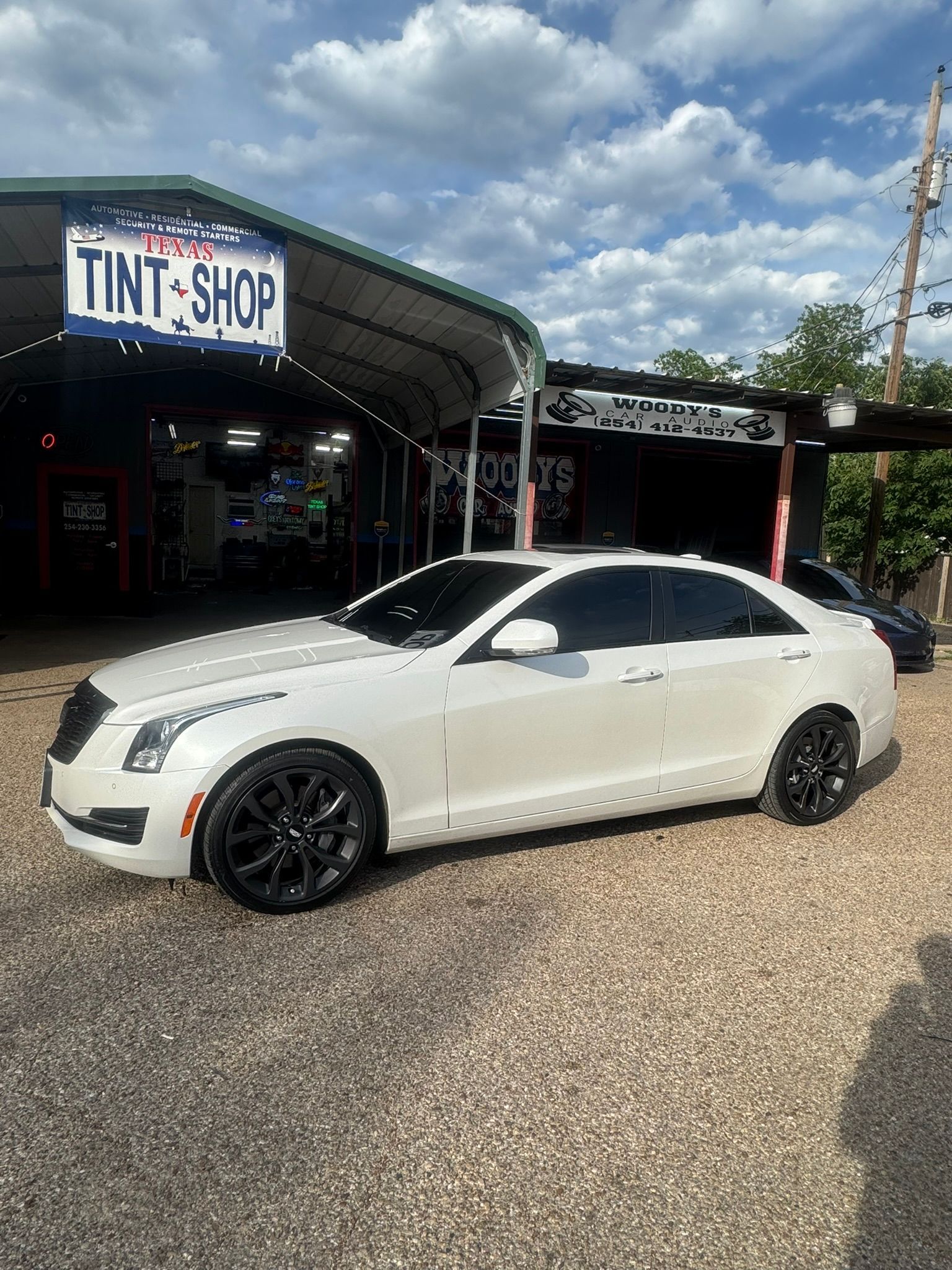 A white car is parked in front of a tint shop.