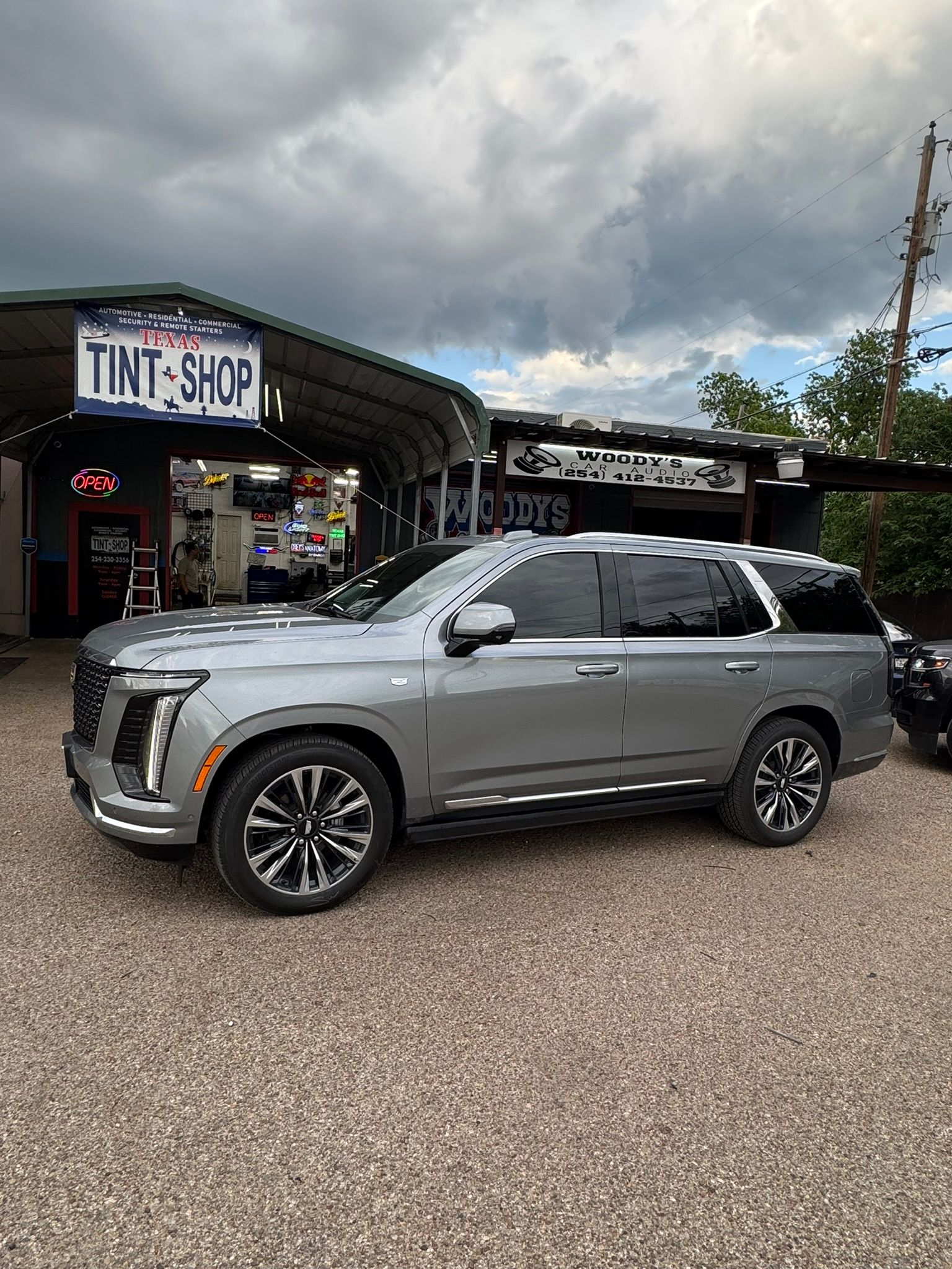A gray suv is parked in front of a tint shop.
