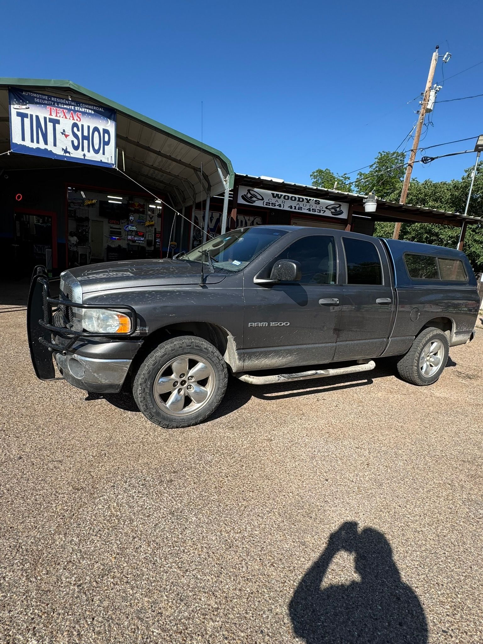 A gray truck is parked in front of a tint shop.