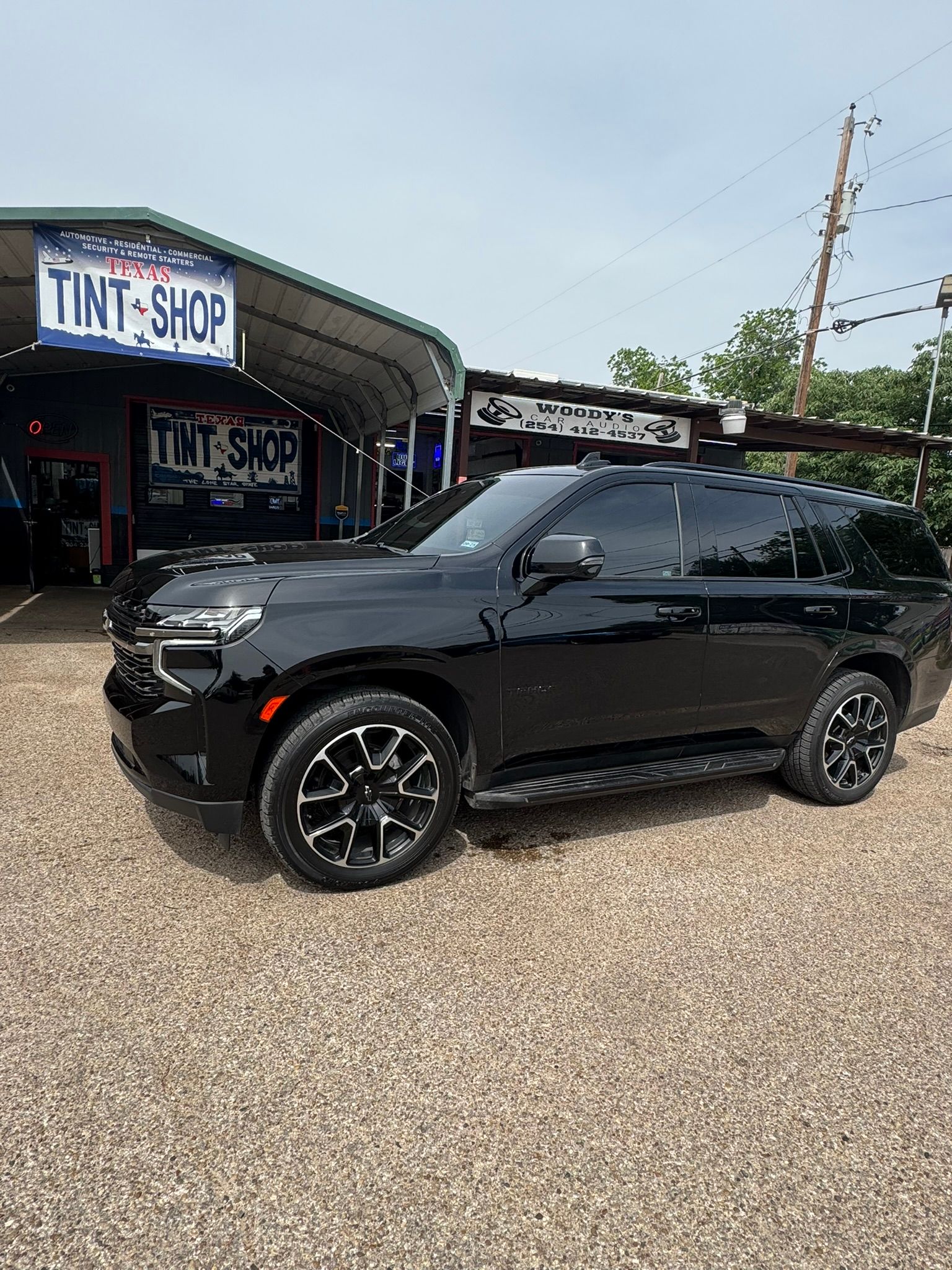 A black suv is parked in front of a tint shop.