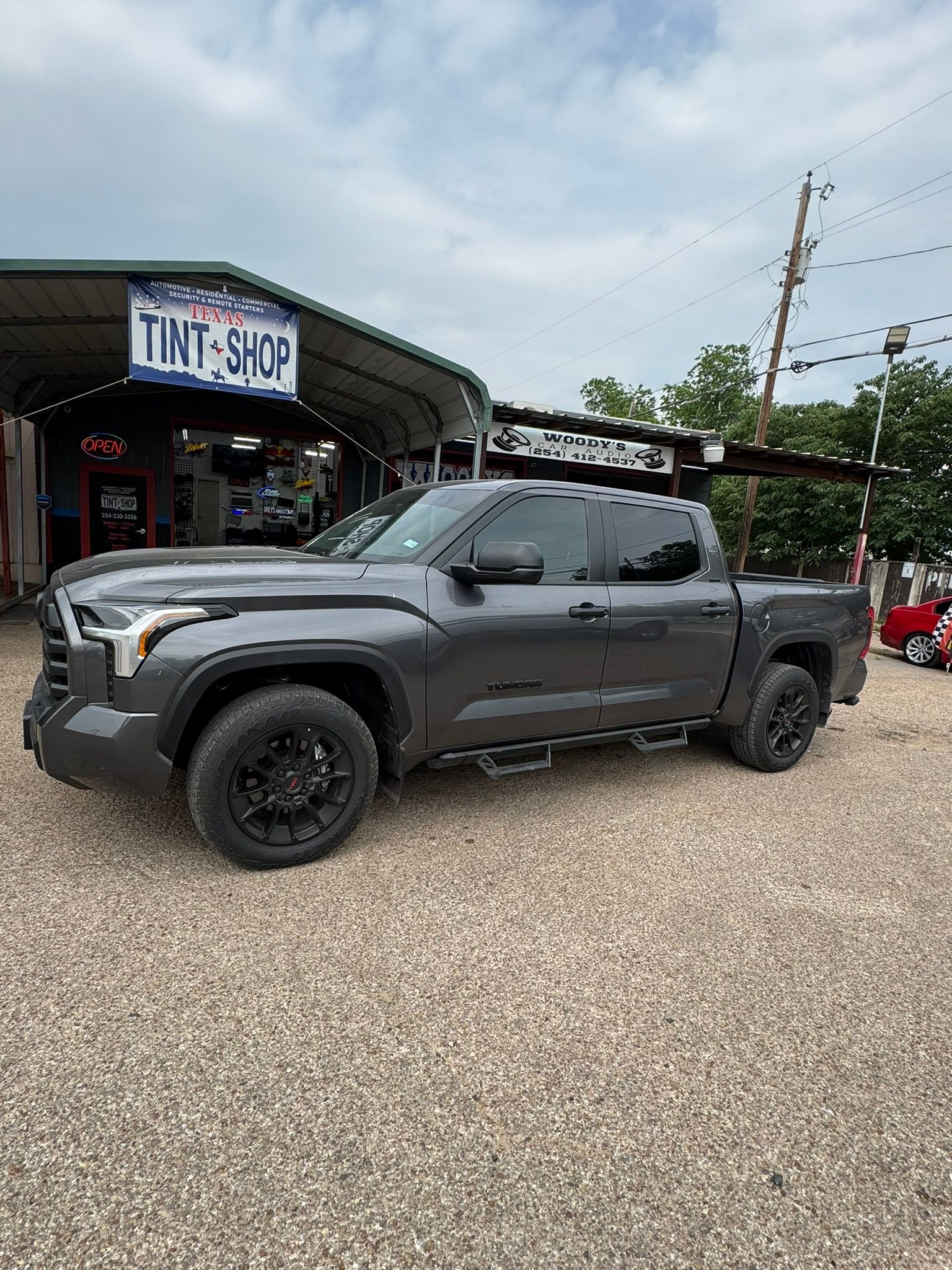 A toyota tundra is parked in front of a tint shop.