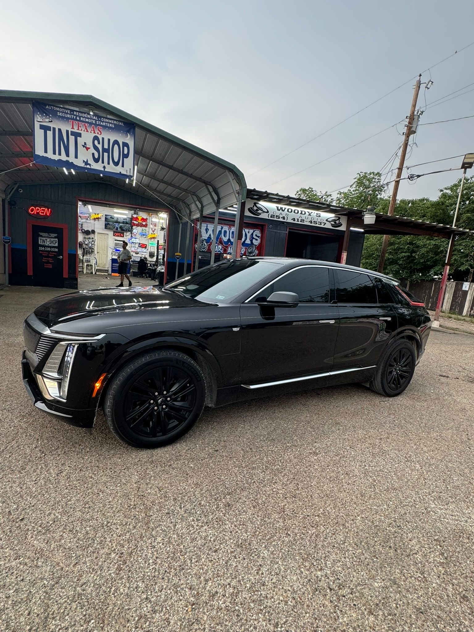 A black car is parked in front of a tint shop.