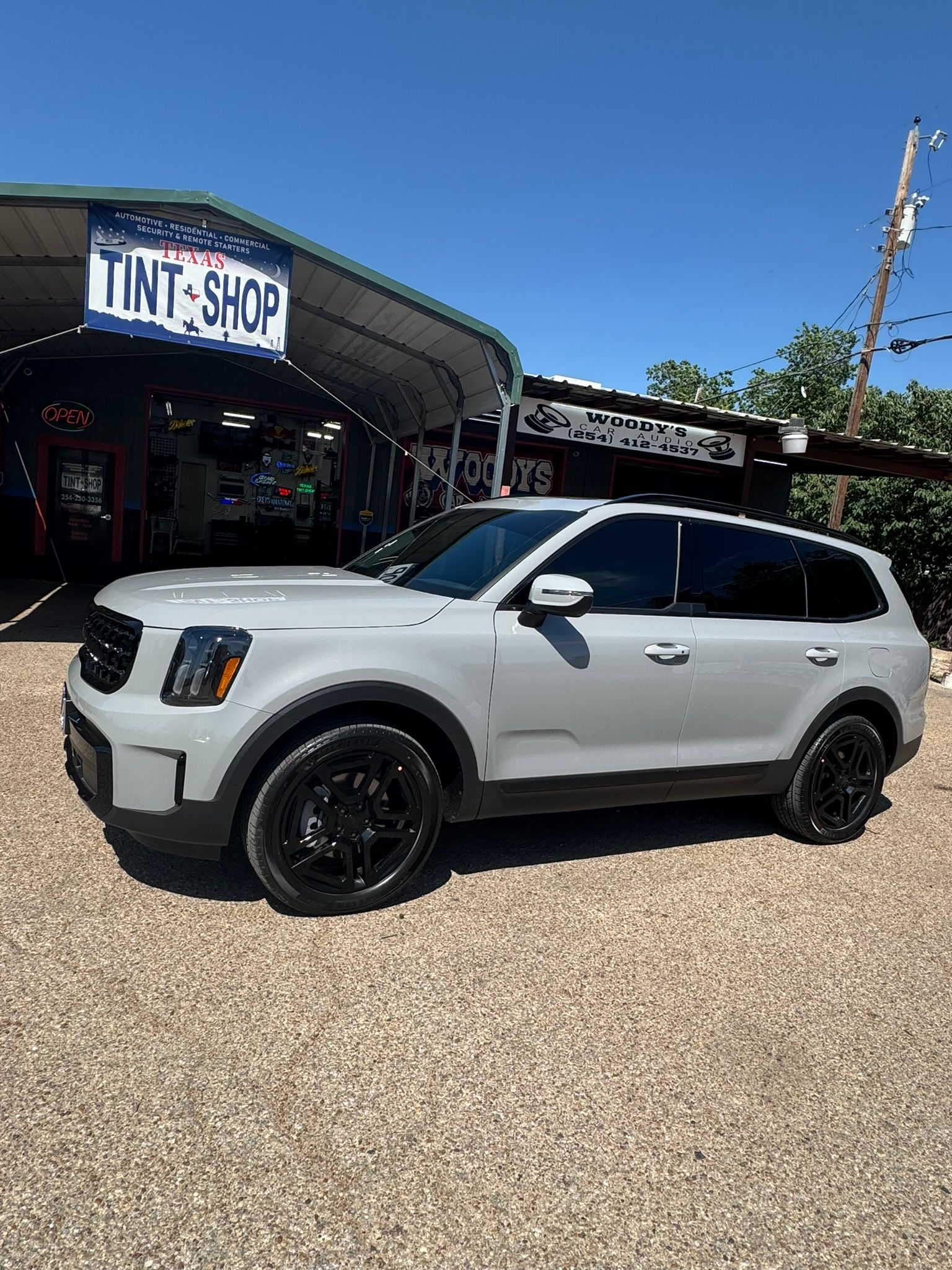 A white suv is parked in front of a tint shop.
