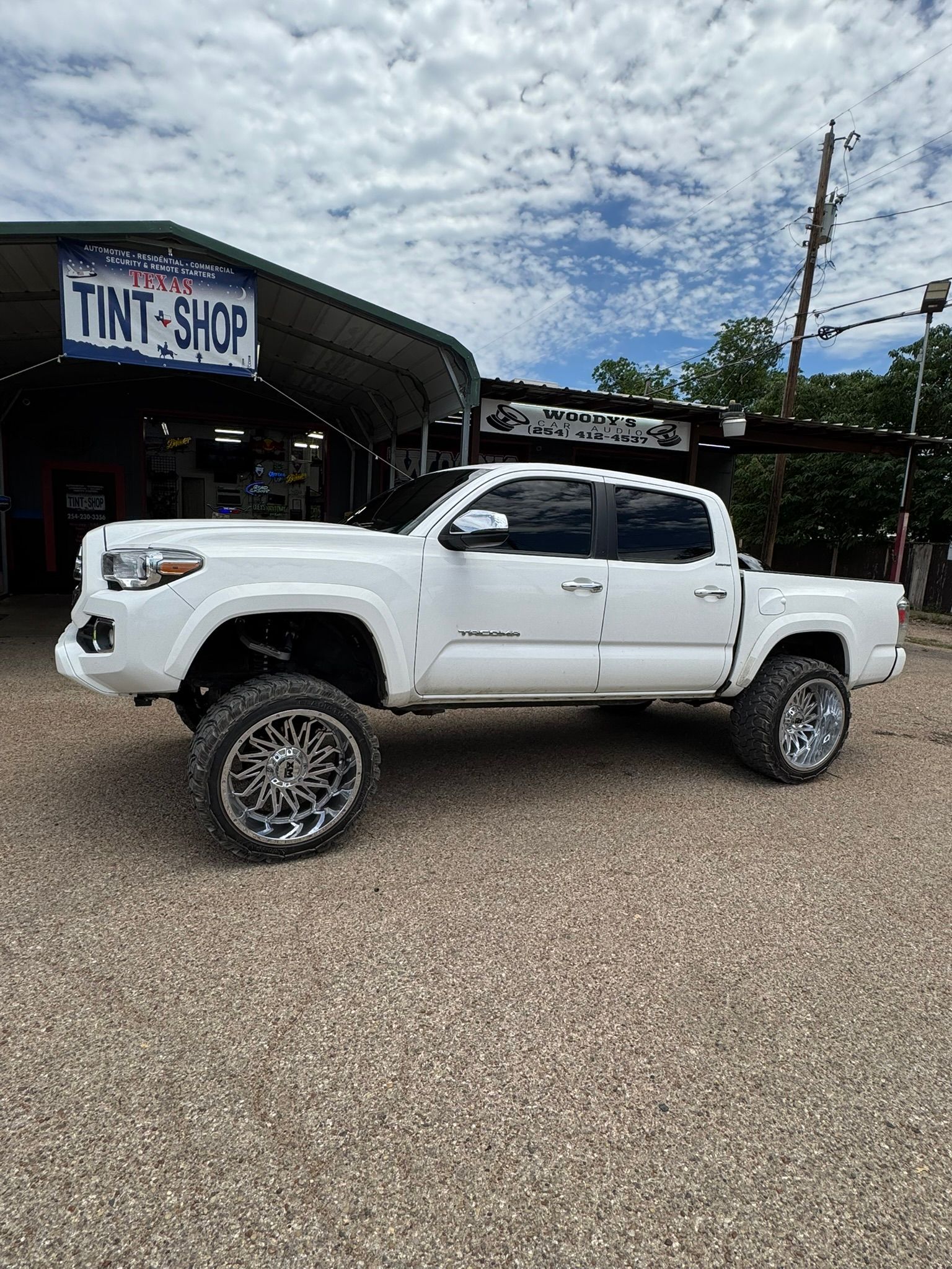 A white truck is parked in front of a tint shop.