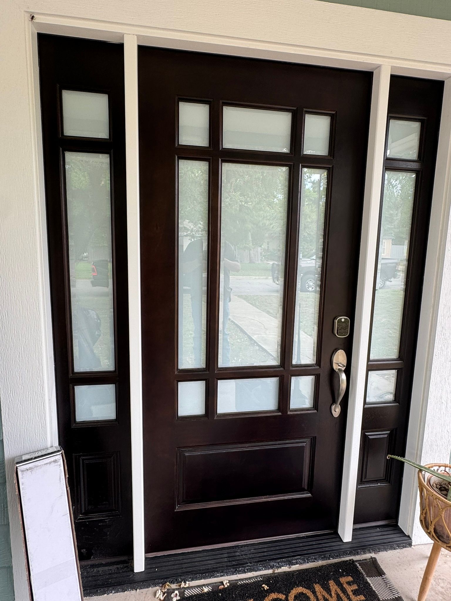 A black front door with a welcome mat in front of it.