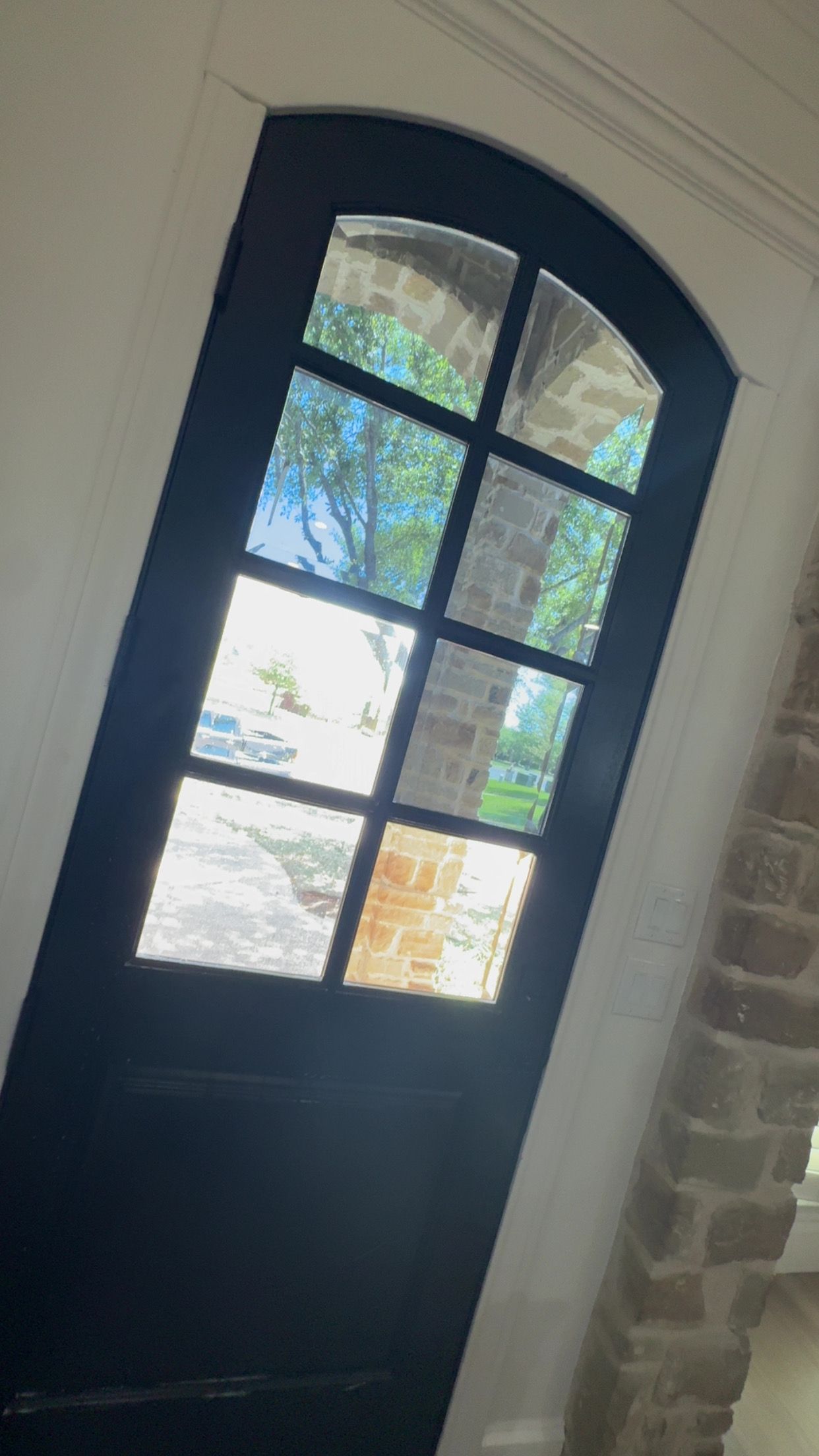 A black door with a stained glass window and a brick wall behind it.
