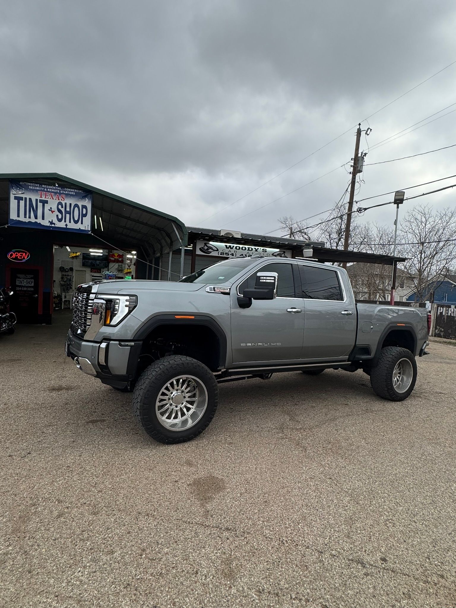 A silver truck is parked in front of a tint shop.