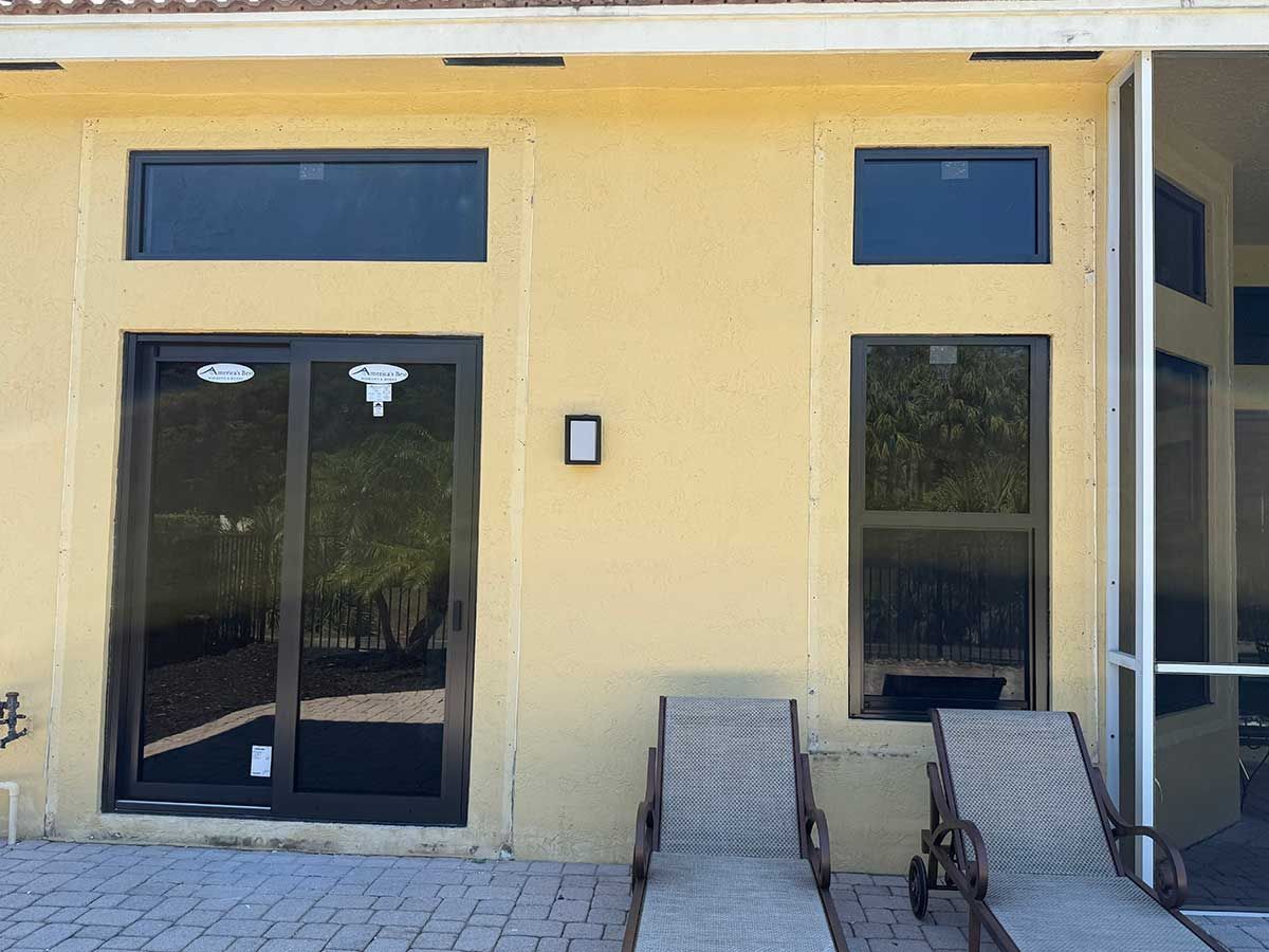 A yellow building with sliding glass doors and chairs in front of it