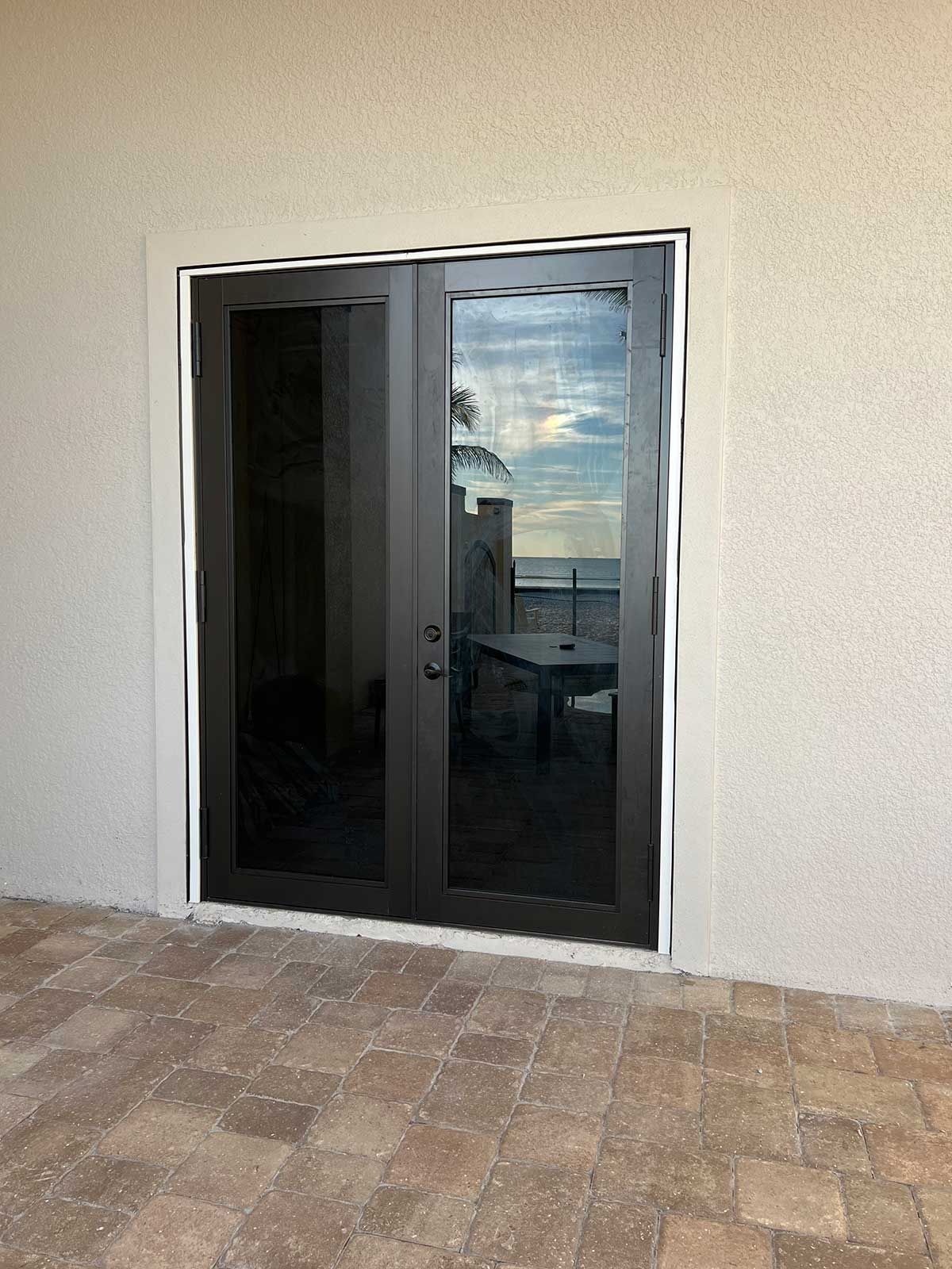 A pair of sliding glass doors leading to a patio with a view of the ocean.