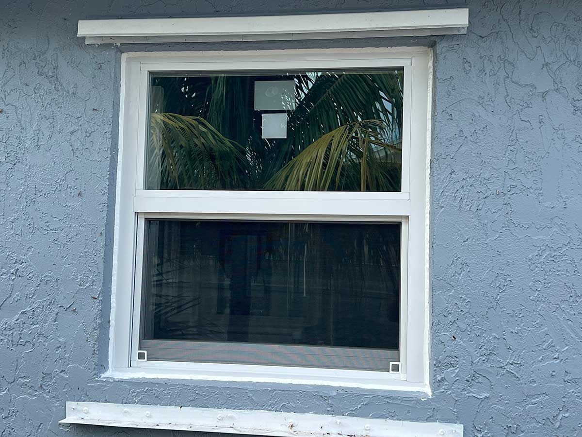 A white window is on the side of a house.