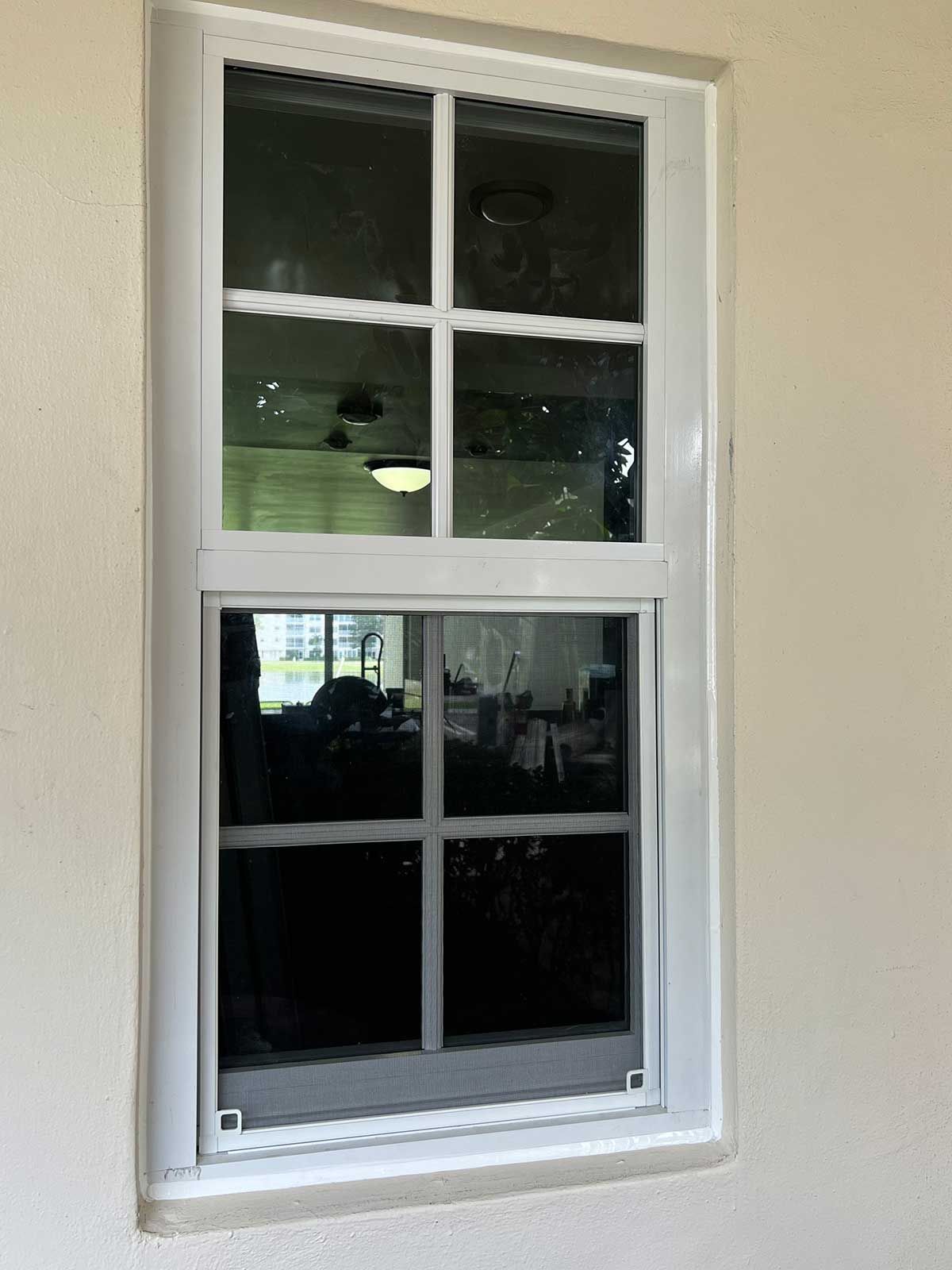 A white window with a black glass is on a white wall.
