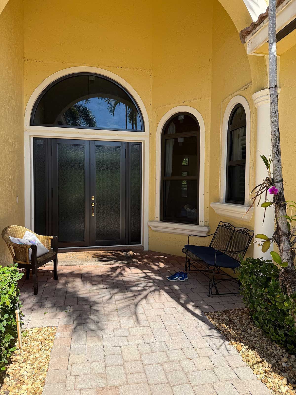 A yellow house with a brick walkway leading to the front door.