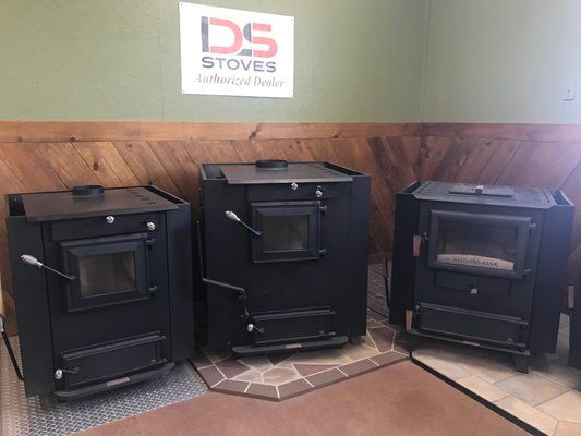 Three black wood-burning stoves on display in a showroom with DS Stoves logo.