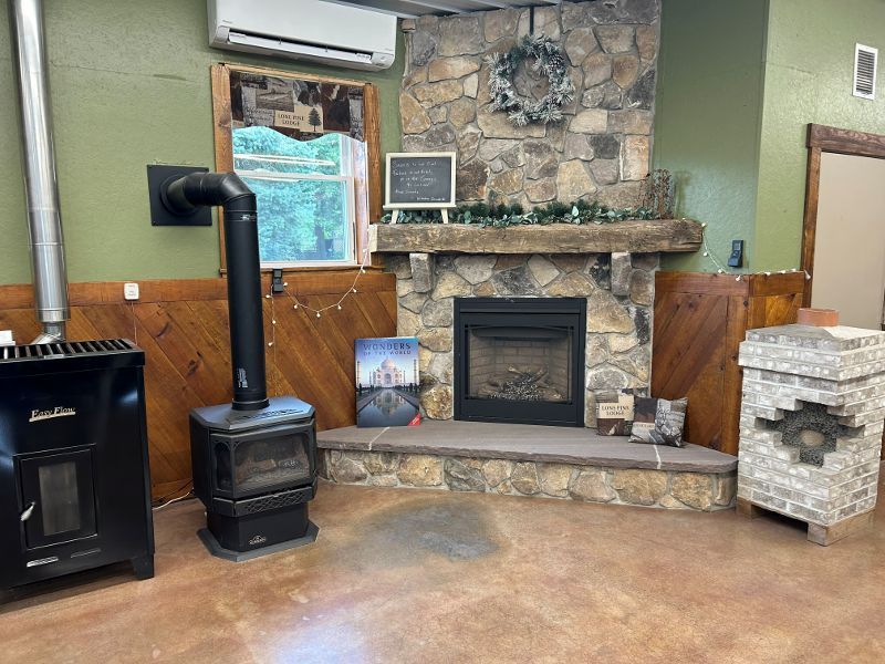 Cozy room with fireplace and two stoves.  Stone and wood accents, green walls.