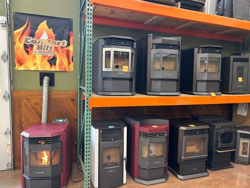 Pellet stoves on display in a store, featuring various colors and sizes, with a 