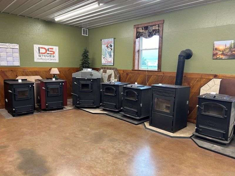 Several black and red wood-burning stoves on display in a showroom.