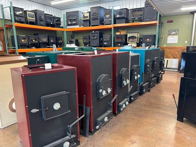 Row of wood stoves in varying colors and styles displayed in a showroom.