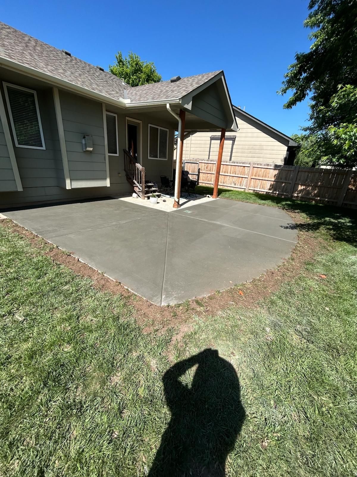 A shadow of a person is cast on the grass in front of a house.