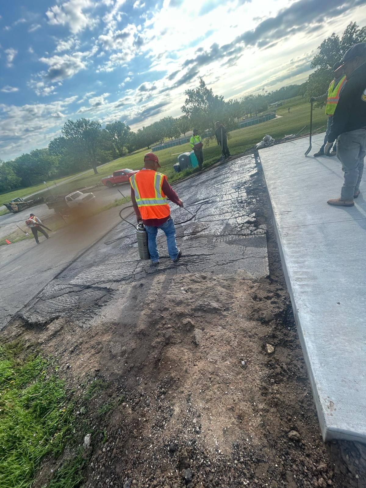 A man in an orange vest is walking down a dirt road.