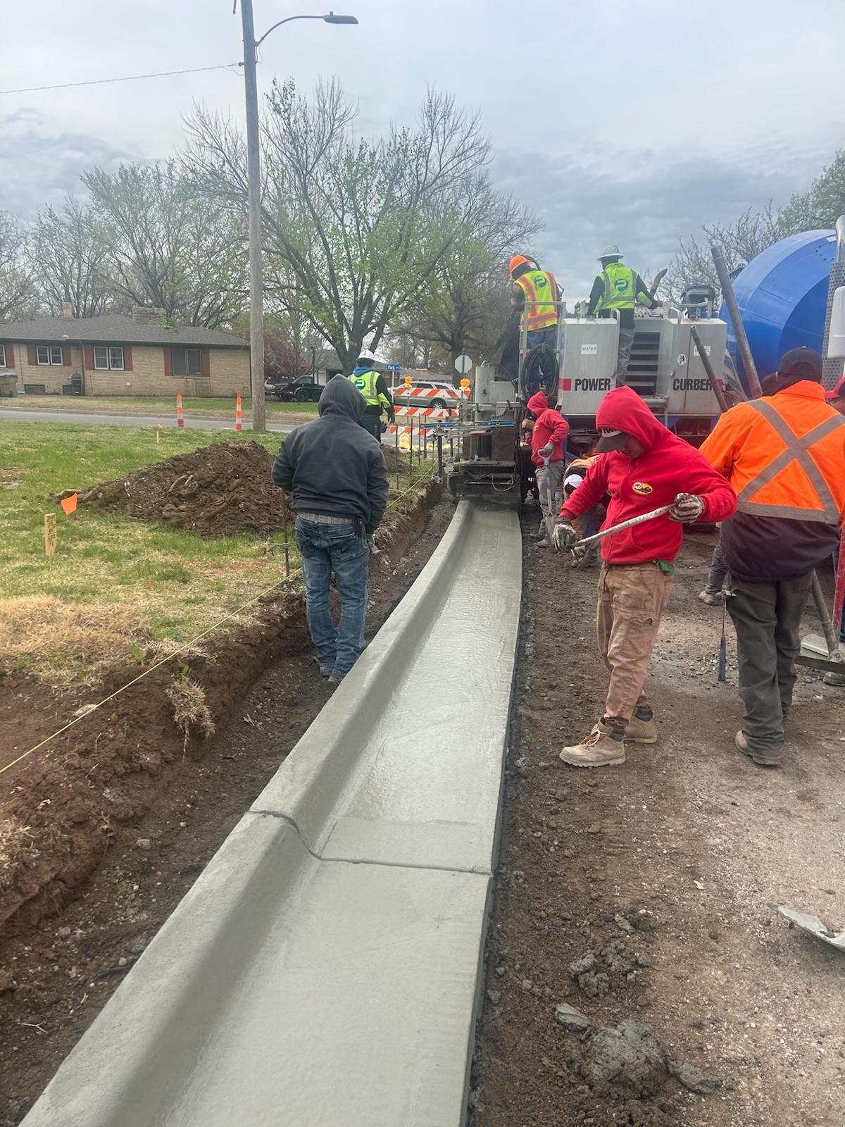 A group of construction workers are working on a sidewalk.