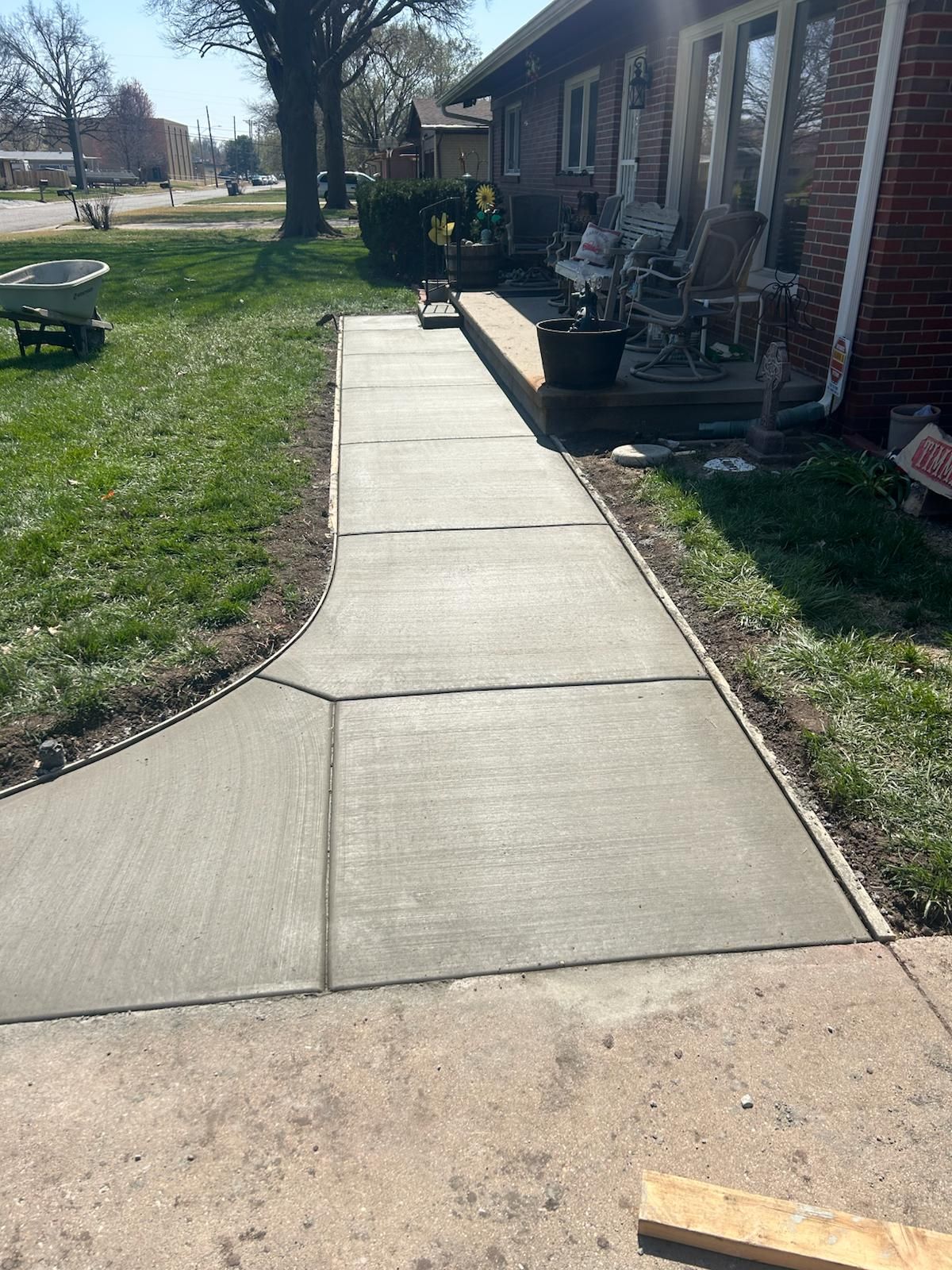 A concrete walkway is being built in front of a brick house.