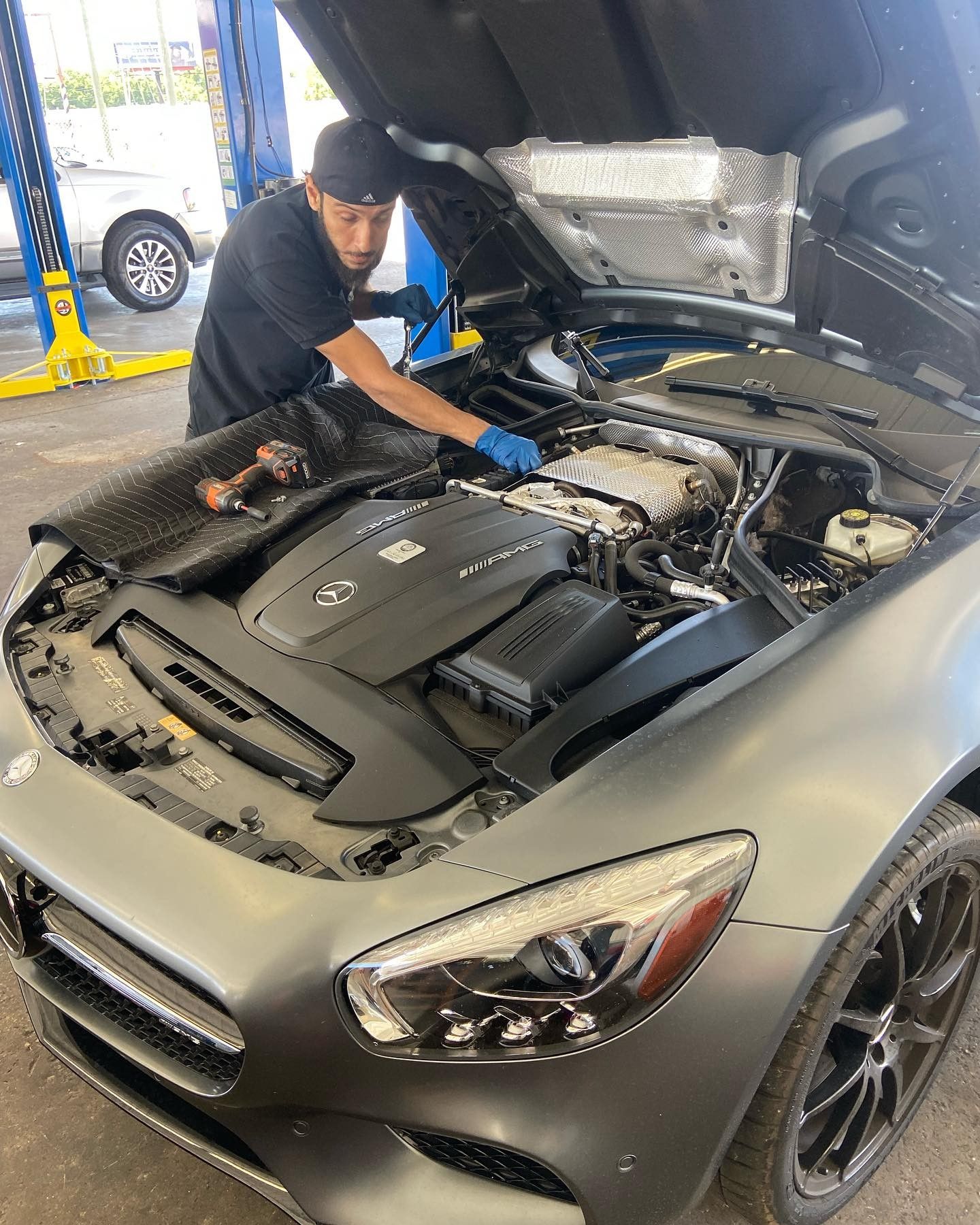 A man is working on the engine of a car with the hood open.