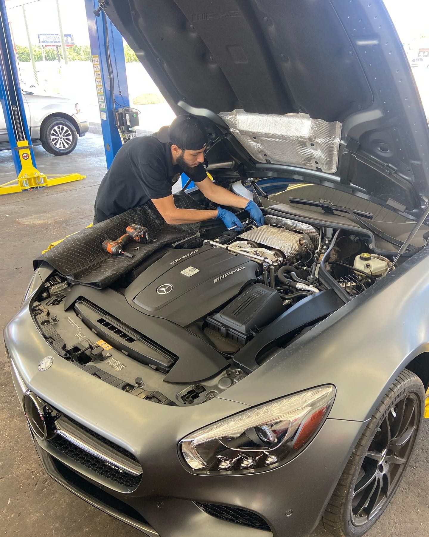 A man is working on the engine of a car with the hood open.