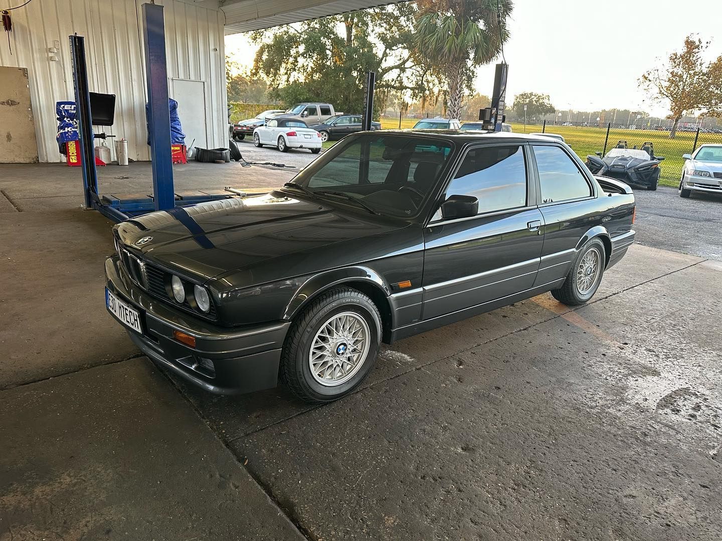 A black bmw is parked in a parking lot next to a building.