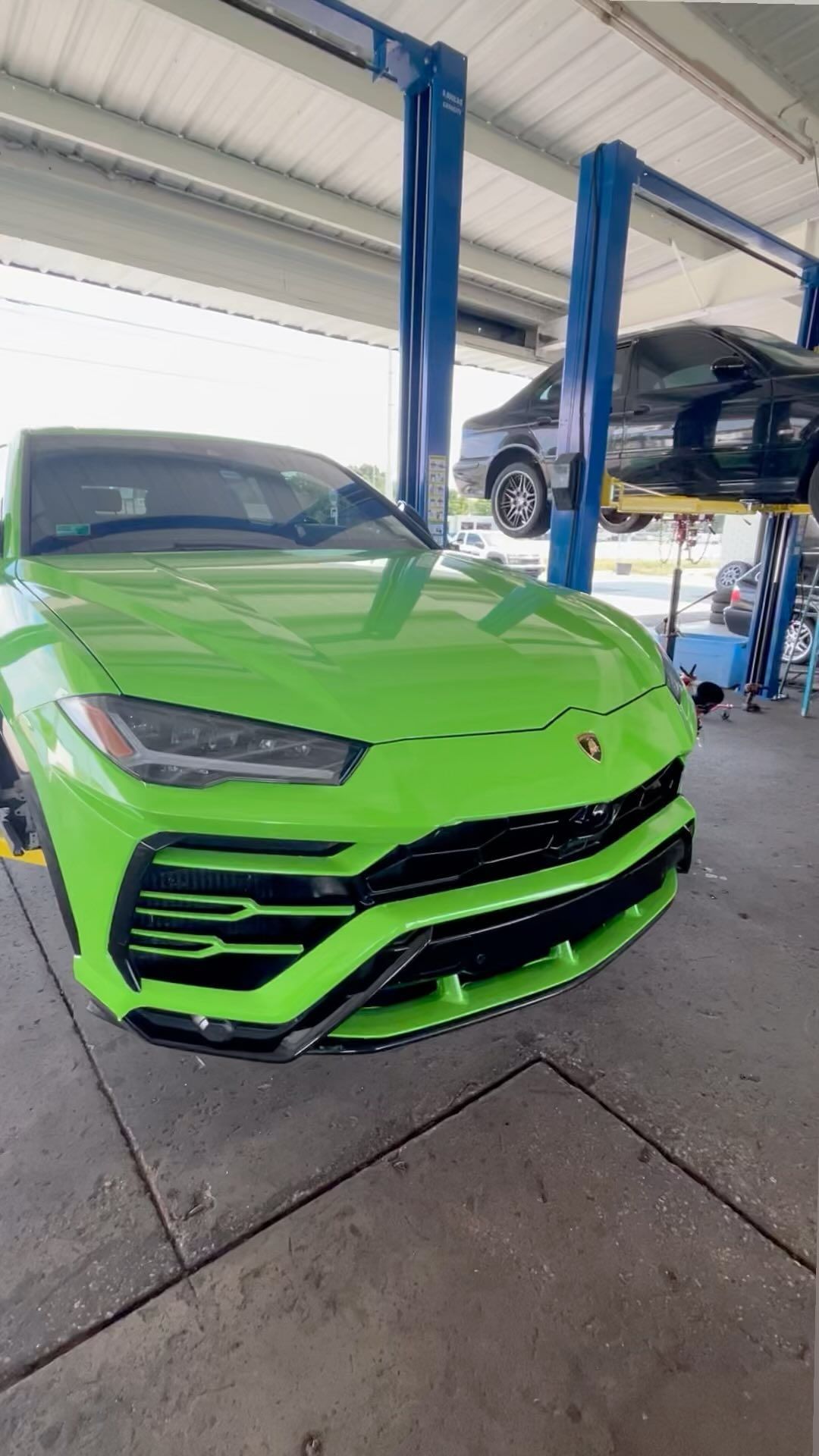 A green lamborghini urus is parked in a garage.